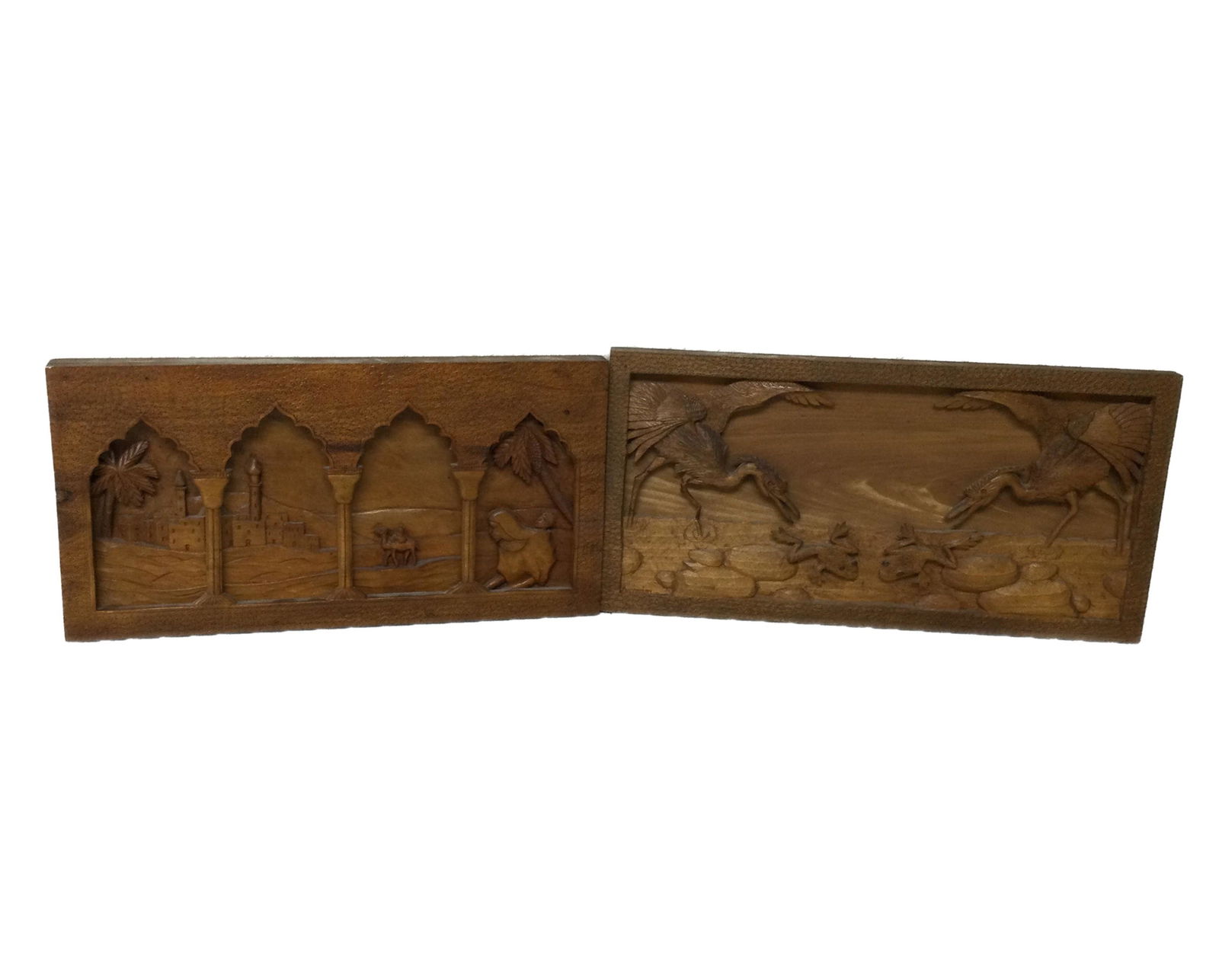 African Pair of Deep Relief Wood Carved Plaques Signed: Antonini (Africa) Pair of Deep Relief Wood Carved Plaques Signed. One plaque depicting 2 cranes trying to catch frogs. The other plaque is of a middle eastern scene in the desert of people heading tow