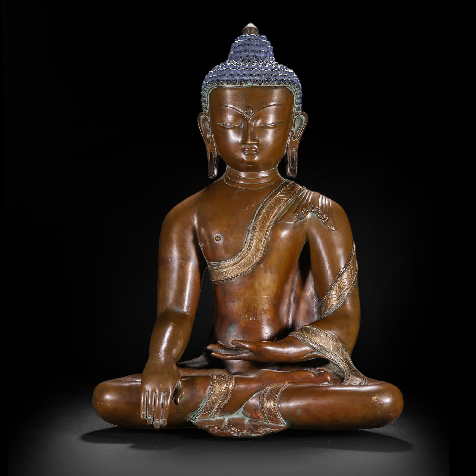 A BRONZE STATUE OF SAKYAMUNI BUDDHA FROM THE QING DYNASTY: H:43cm(16.93in) W:32cm(12.60in) Weight:9800g(21.61lb)This statue is cast in copper. Sakyamuni Buddha sits in the full lotus position on a lotus throne, with a calm and solemn face and a peaceful demea