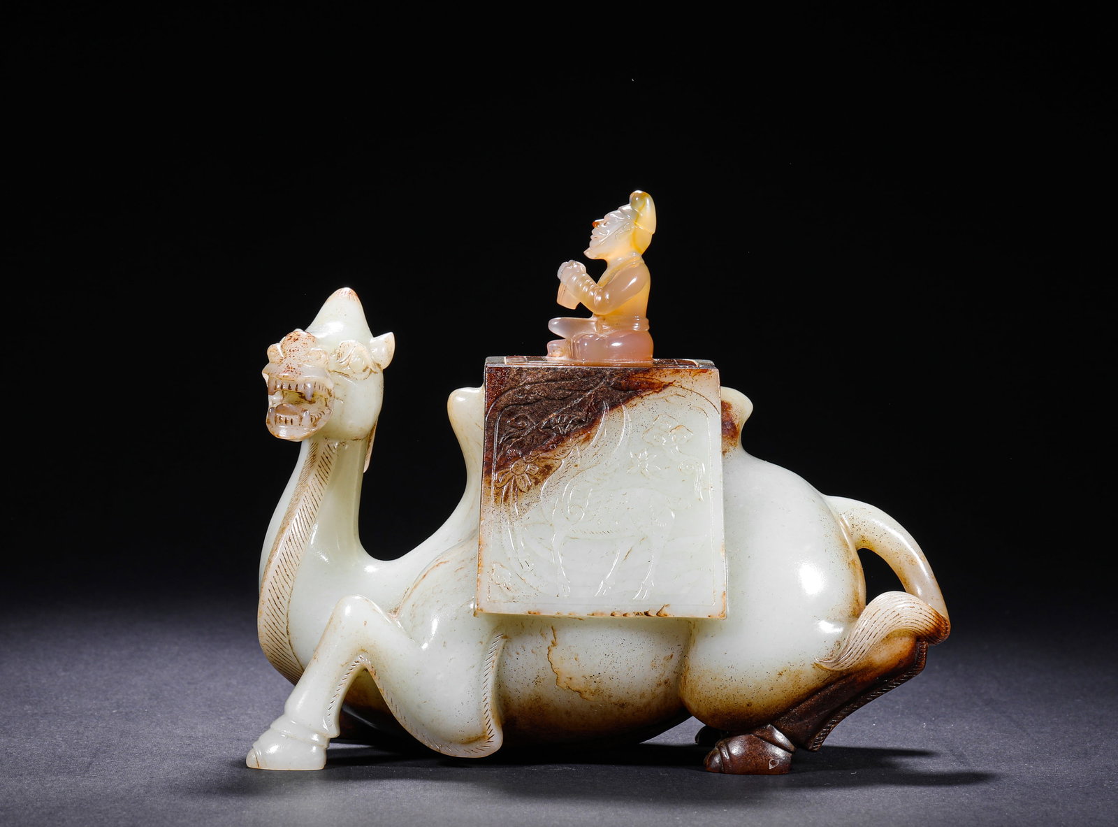 TANG DYNASTY HETIAN JADE HU PEOPLE RIDING CAMELS: H:18cm (7.09in) W:18cm (7.09in) Weight:1570g (3.46lb)Carved from single whole jade, this piece depicts a recumbent camel. The fine moist white jade is covered with natural aged yellowish-brown infiltr