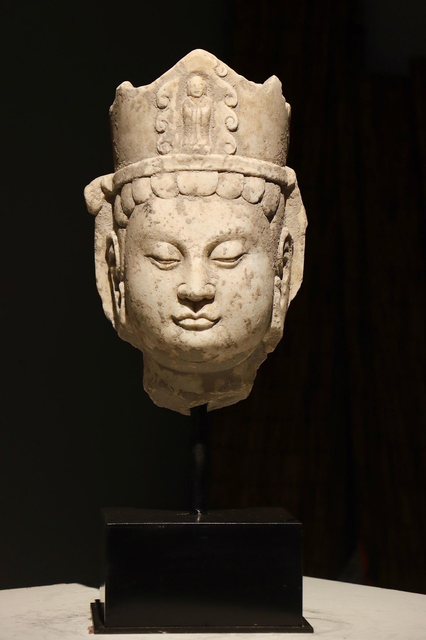 A LARGE WHITE MARBLE BUDDHA HEAD FROM THE NORTHERN WEI DYNASTY: H:60cm(23.62in)H:39cm(15.35in)This is a fragmented head sculpture of Bodhisattva carved from white marble of late Northern Wei Dynasty. The marble texture is delicate and smooth. It wears a tall elabo