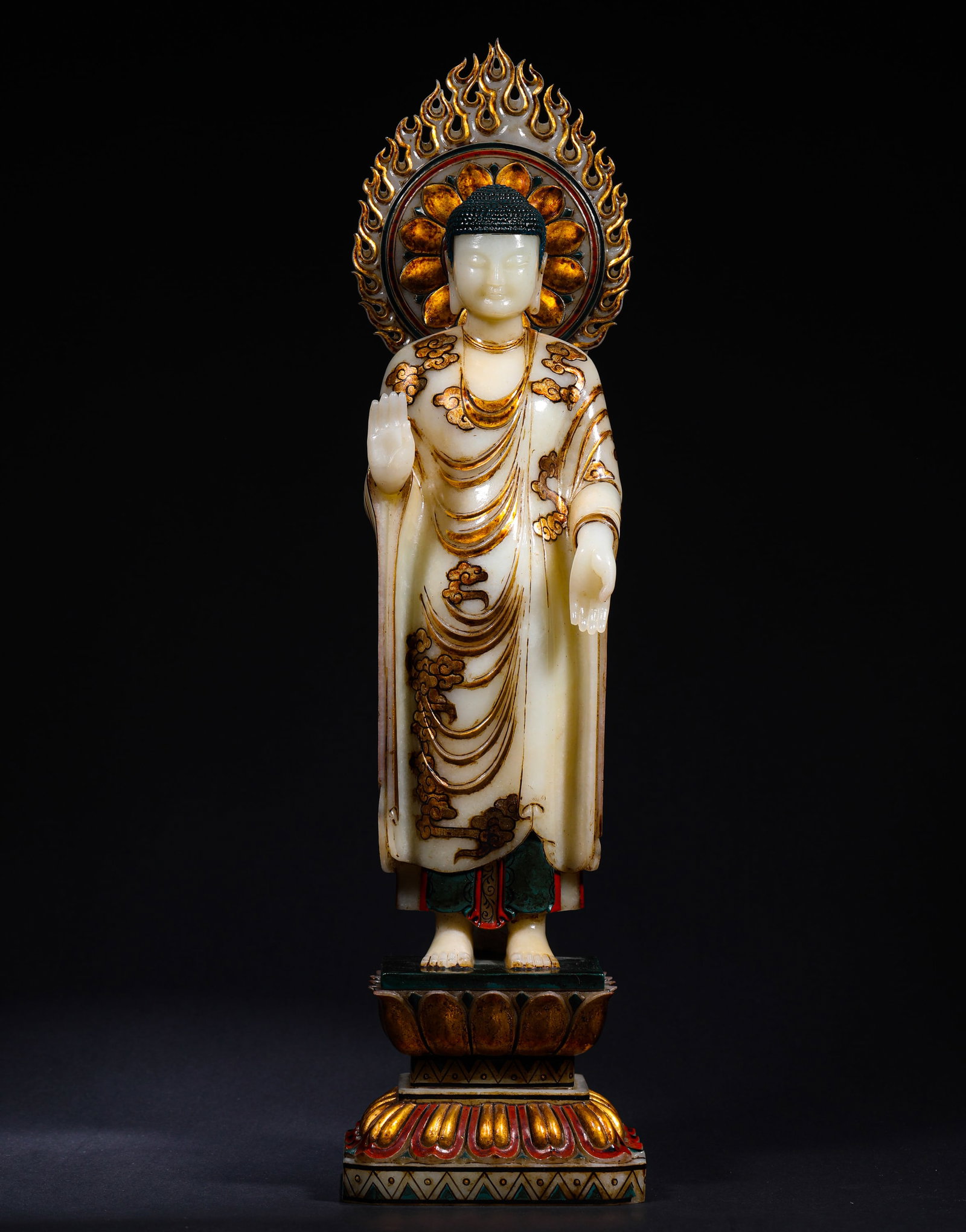 A WHITE JADE STATUE OF SAKYAMUNI BUDDHA FROM HETIAN DURING THE QING DYNASTY: H:44cm(17.32in) W:11cm(4.33in) Weight:4110g(9.06lb)This artifact is a round-carved standing statue of Sakyamuni, with a compassionate and serene expression. The robe is decorated with cloud motifs in 