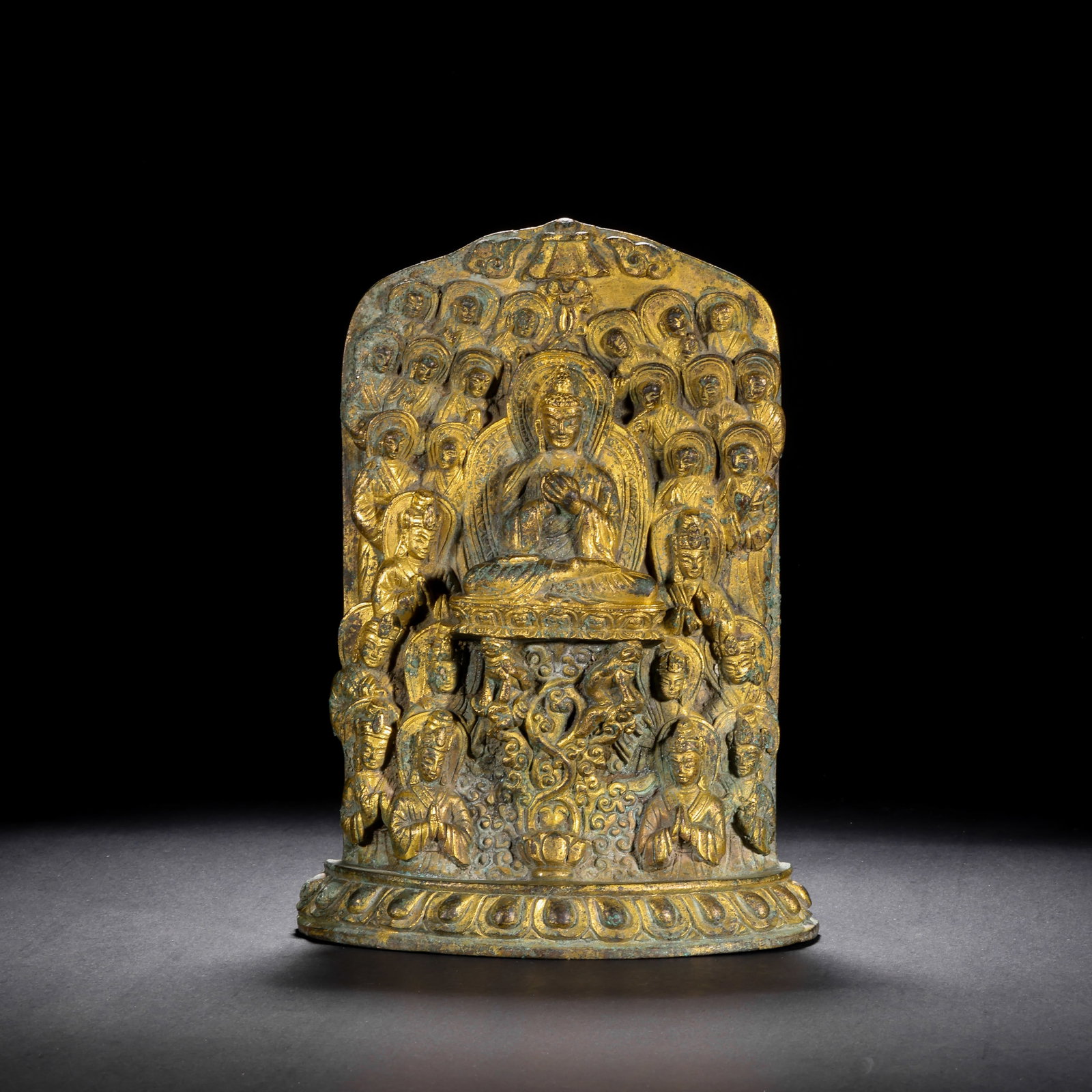 A GILDED BRONZE STATUE STELE OF TEN THOUSAND BUDDHAS PAYING HOMAGE TO THE EMPEROR IN THE MING: H:20cm(7.87in) W:14.5cm(5.71in) Weight:1710g(3.77lb)This stele is cast in bronze and gilded. The main deity Sakyamuni Buddha sits in the lotus position on a lotus throne, with hands in mudra and a sol
