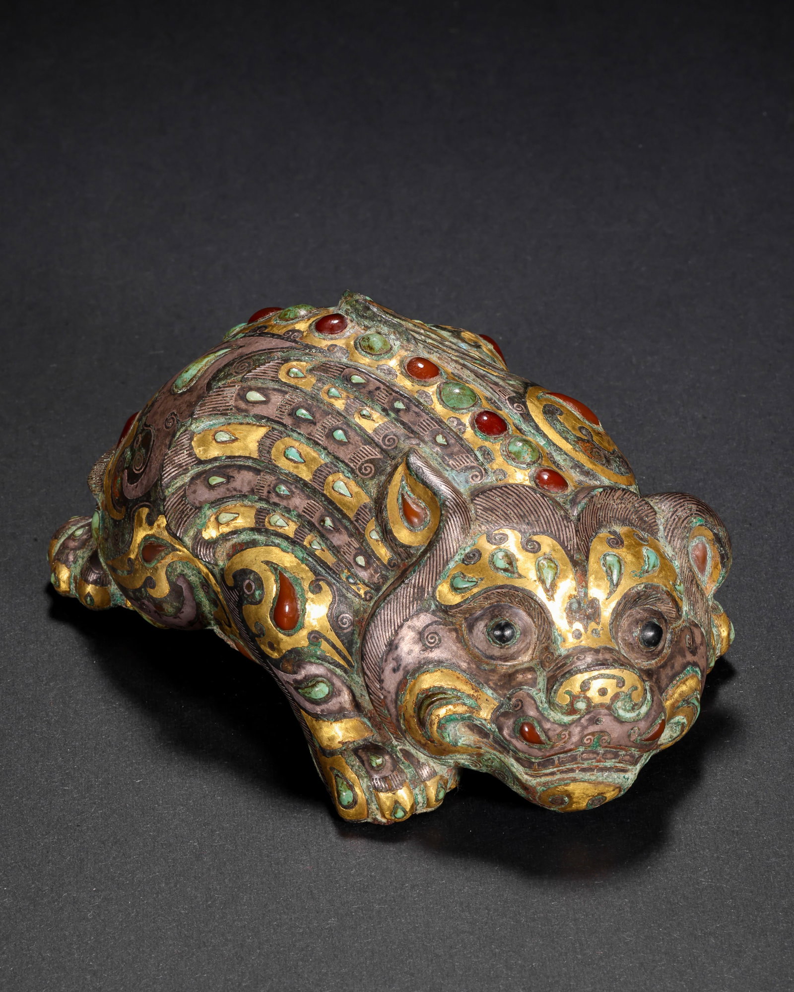 COPPER INLAID WITH GOLD AND SILVER INLAID WITH GEMSTONES AUSPICIOUS BEAST TOWN OF THE HAN DYNASTY: H:4cm(1.57in) W:10cm(3.94in) Weight:460g(1.01lb)This artifact is cast in bronze, fully decorated with patterns on the beast's body using gold and silver inlay technique, inlaid with red and green gems