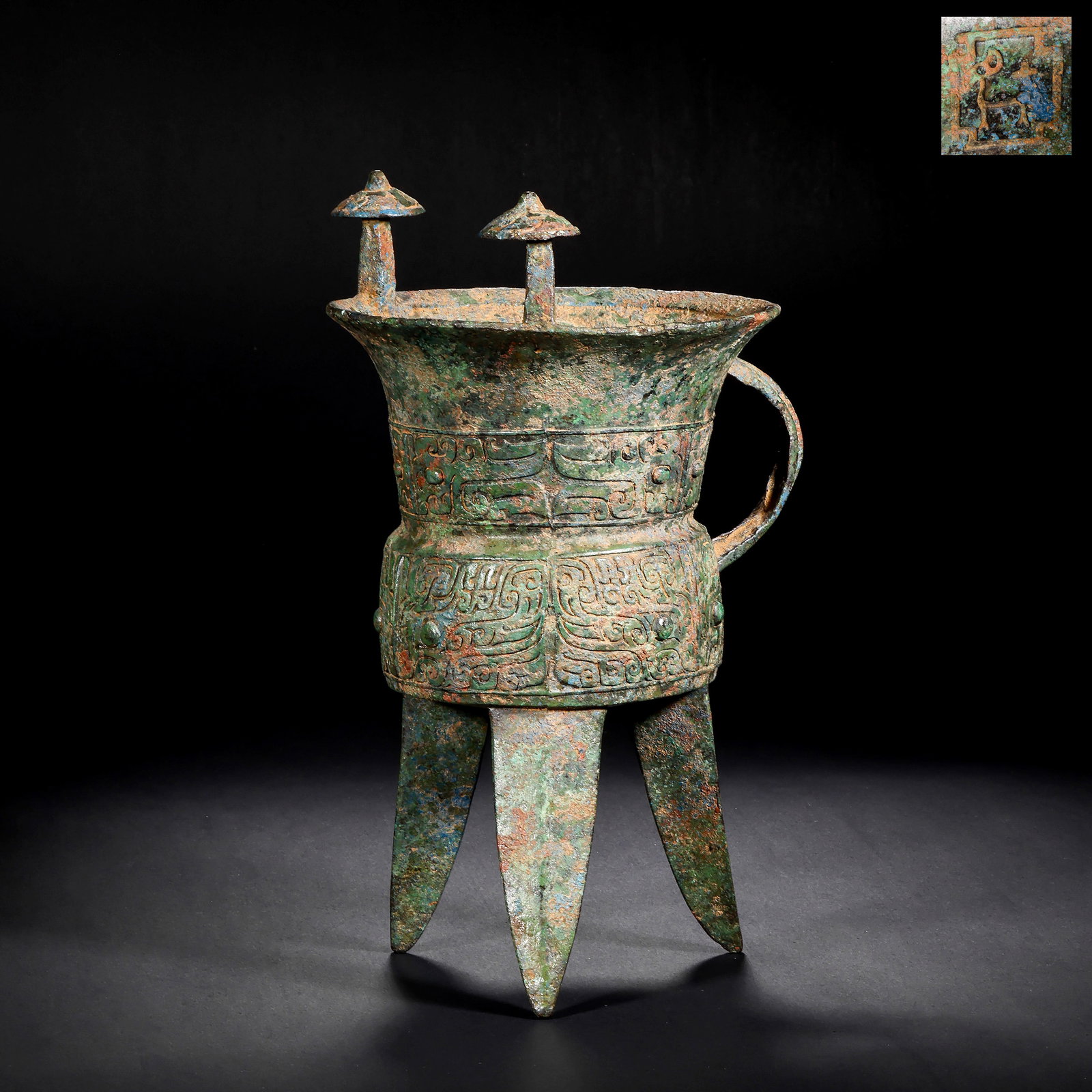 SHANG DYNASTY BRONZE ANIMAL FACE PATTERN : H:25.0cm(9.84in) W:16.5cm(6.50in) Weight:1820g(4.01lb)This vessel is cast in bronze, with a wide mouth, narrow waist, three pointed feet, two umbrella-shaped pillars on the rim, and a handle on the si