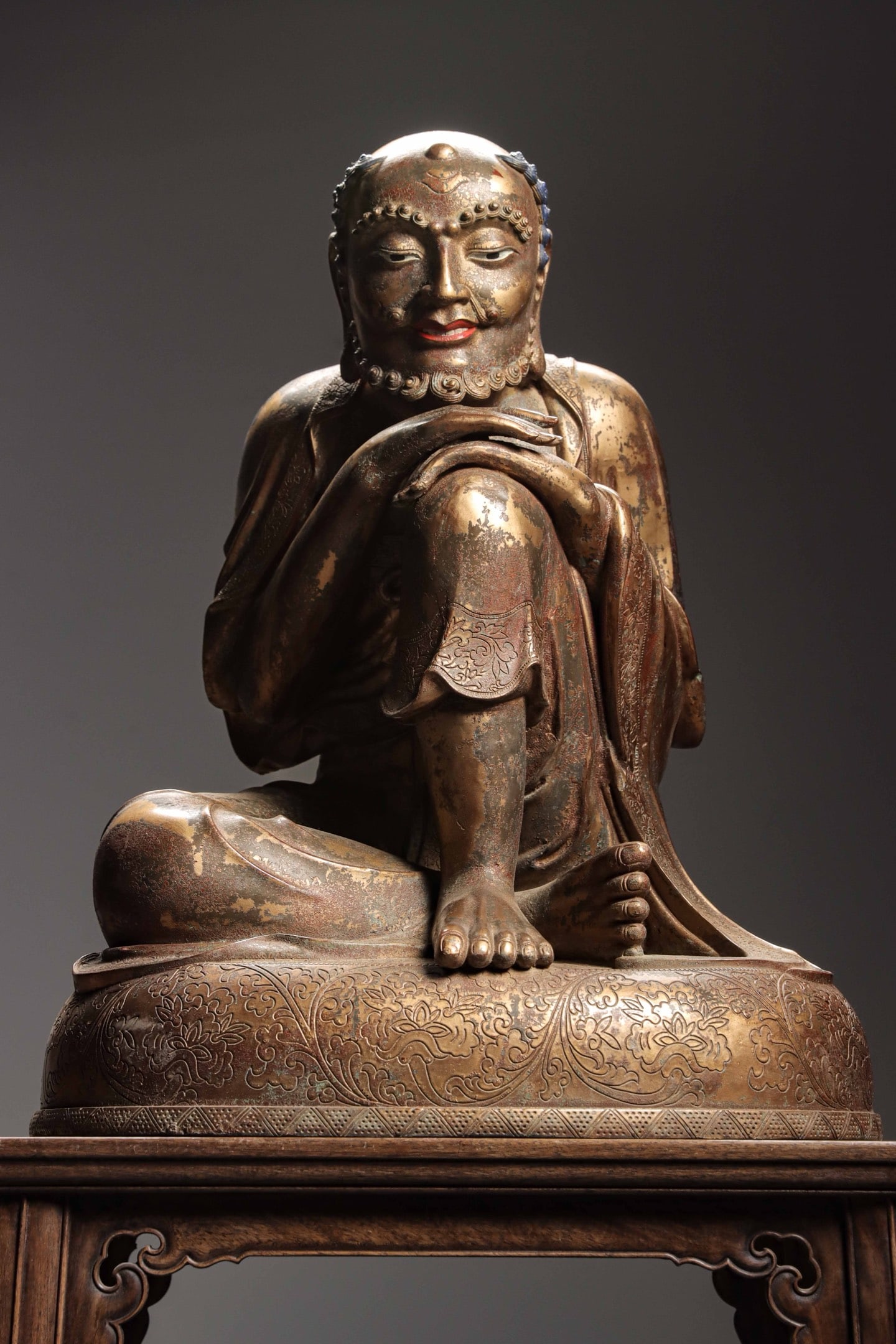 A GILDED BRONZE STATUE OF THE SNOW MOUNTAIN BODHISATTVA FROM THE MING DYNASTY: Weight:23300g(51.37lb)H:66cm(25.98in)W:52.6cm(20.71in)T:44cm(17.32in)With arms crossed and resting on knee, it has a leisurely relaxed figure with naturally draped robe carved with delicate hidden scr