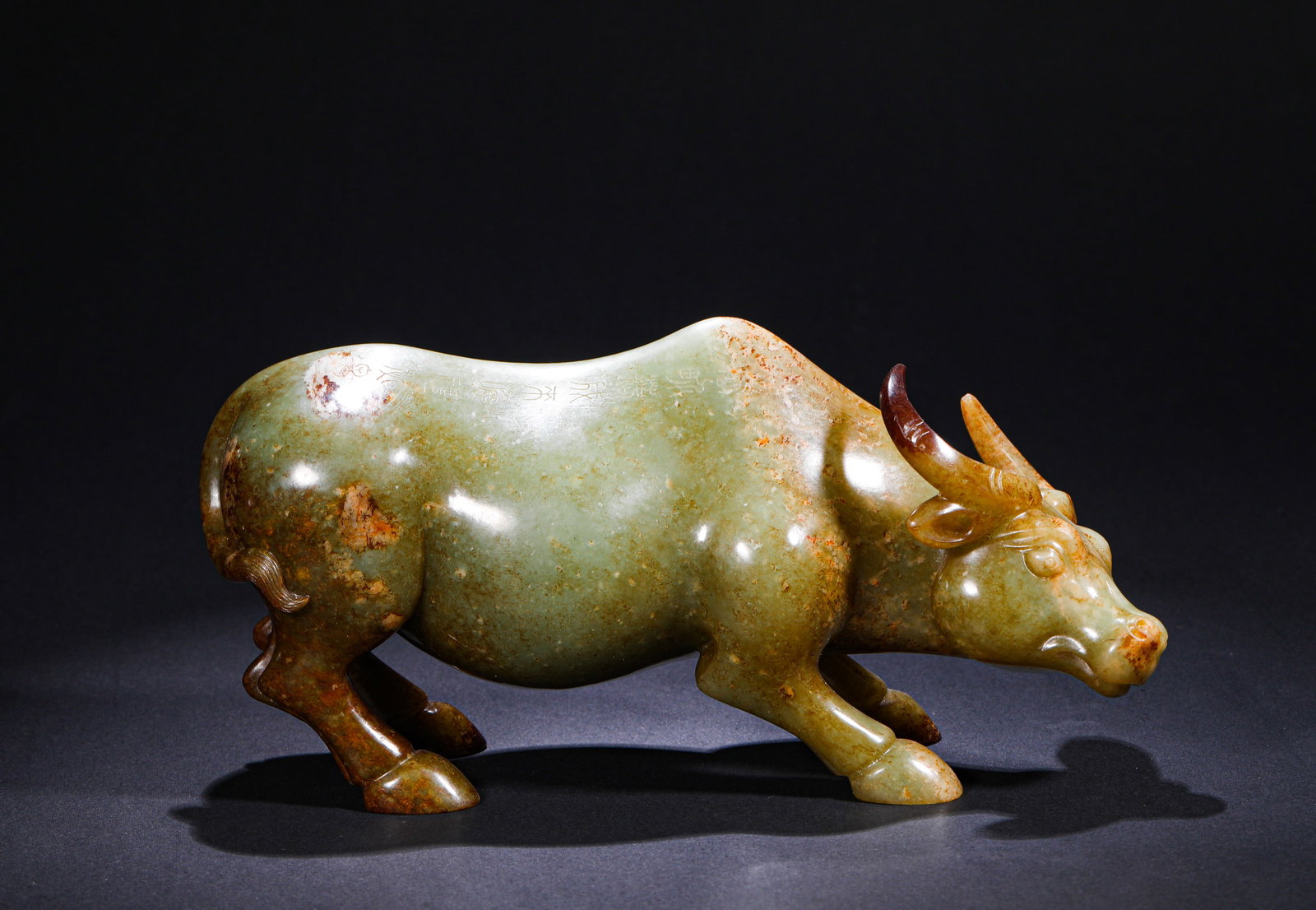 QING DYNASTY INSCRIPTION HETIAN JADE OX: H:14cmW:23cmWeight:2530g This is a recumbent jade buffalo carving crafted from greenish-white jade in round sculpture. Made of warm greenish-white jade, the buffalo is carved in a prone posture with a