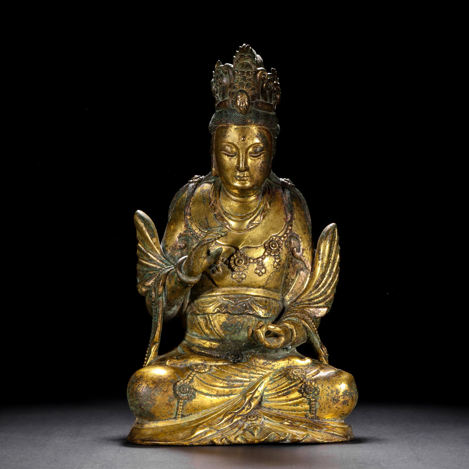 A SEATED STATUE OF GUANYIN BODHISATTVA IN GILDED COPPER FROM THE MING DYNASTY: H:33cm(12.99in) W:17cm(6.69in) Weight:4960g(10.93lb)This statue is cast in bronze and gilded. Guanyin Bodhisattva sits in the lotus position, wearing a precious crown with a compassionate face, smooth