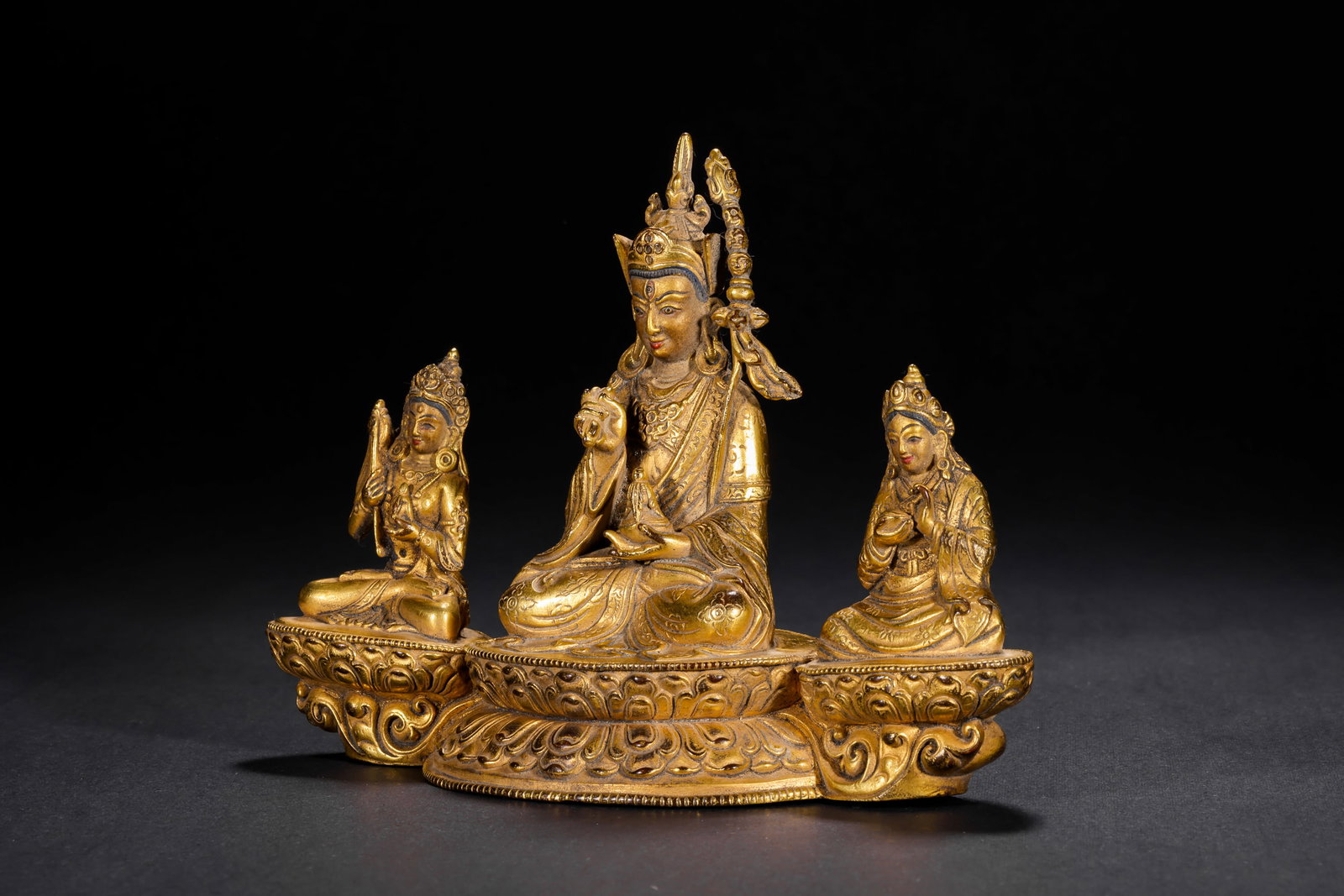 THREE GILDED BRONZE STATUES OF PADMASAMBHAVA FROM THE QING DYNASTY: H:11.5cm(4.53in) W:15.0cm(5.91in) Weight:670g(1.48lb)This set of statues is cast in bronze and gilded. The main statue Padmasambhava sits in lotus position on a lotus pedestal, wearing a treasure crow