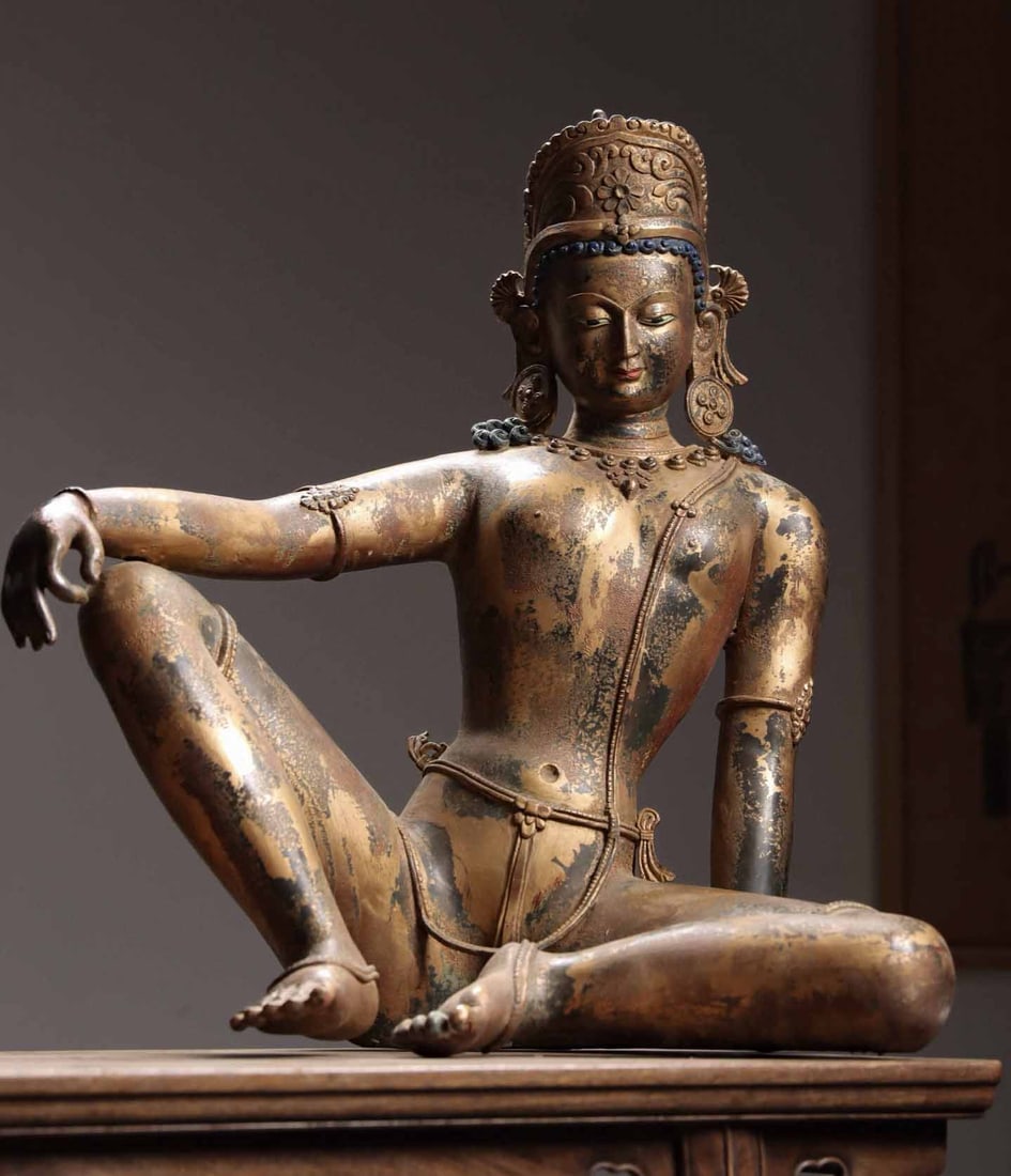 MING DYNASTY TIBETAN TRADITION • GILT BRONZE STATUE OF AVALOKITESVARA: Weight:20450g(45.09lb)H:58cm(22.83in)W:56cm(22.05in)T:30cm(11.81in)This sculpture depicts the deity in a relaxed casual sitting posture, wearing an elaborate crown with gentle merciful facial features