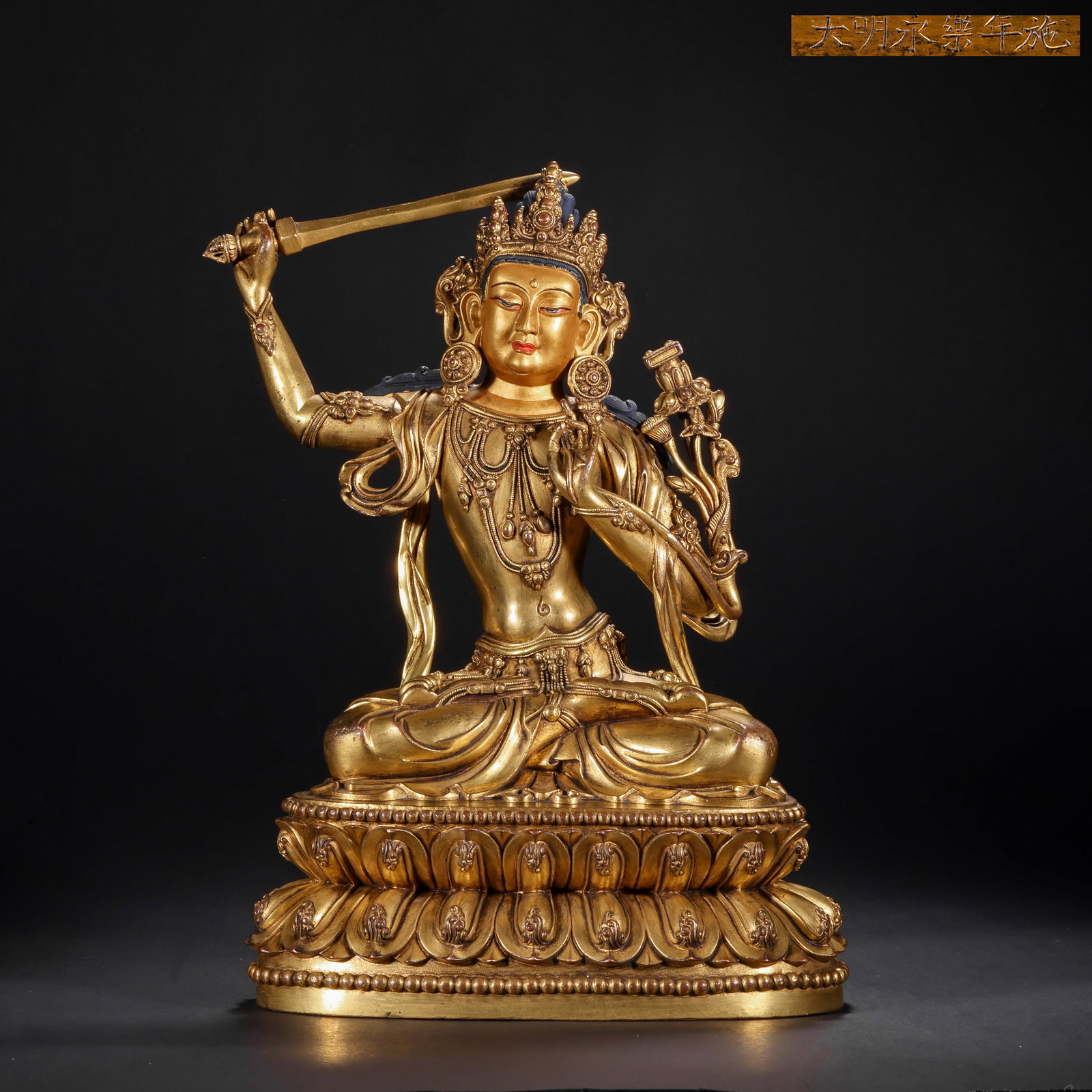 A GILDED BRONZE SEATED STATUE OF MANJUSRI BODHISATTVA FROM THE MING DYNASTY: H:28.0cm(11.02in) W:20.0cm(7.87in) Weight:3320g(7.32lb)This statue is cast with gilded bronze on a copper core. Manjusri Bodhisattva sits in the full-lotus posture on a throne supported by upward-faci