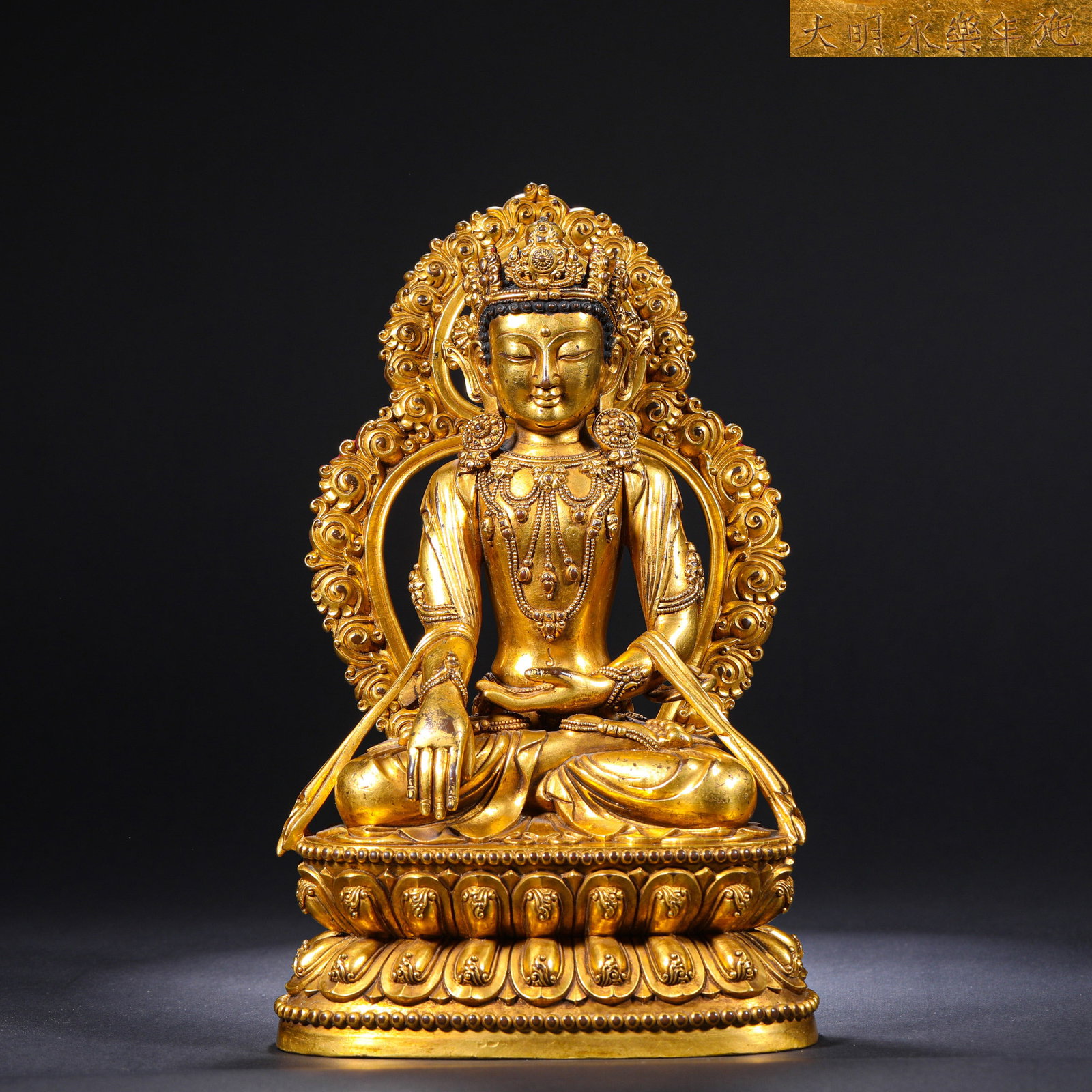 A GILDED BRONZE SITTING STATUE OF A MOTIONLESS BUDDHA FROM YONGLE OF THE MING DYNASTY: H:24cm(9.45in)W:14cm(5.51in)Weight:3110g This is a gilded bronze seated statue of Akshobhya (the Immovable Buddha) from the Yongle period of the Ming Dynasty, inscribed with "Made and offered in the Y