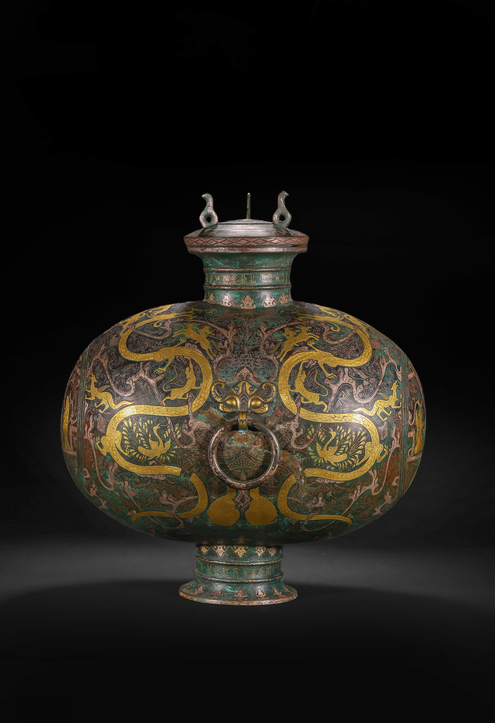 A FLAT POT WITH COPPER INLAID GOLD AND SILVER DRAGON AND PHOENIX PATTERNS FROM THE WARRING STATES: H:44.0cm(17.32in) W:37.0cm(14.57in) Weight:6890g(15.19lb)This vessel is cast in bronze, fully decorated with dragon, phoenix and auspicious beast patterns using gold and silver inlay technique. The ve