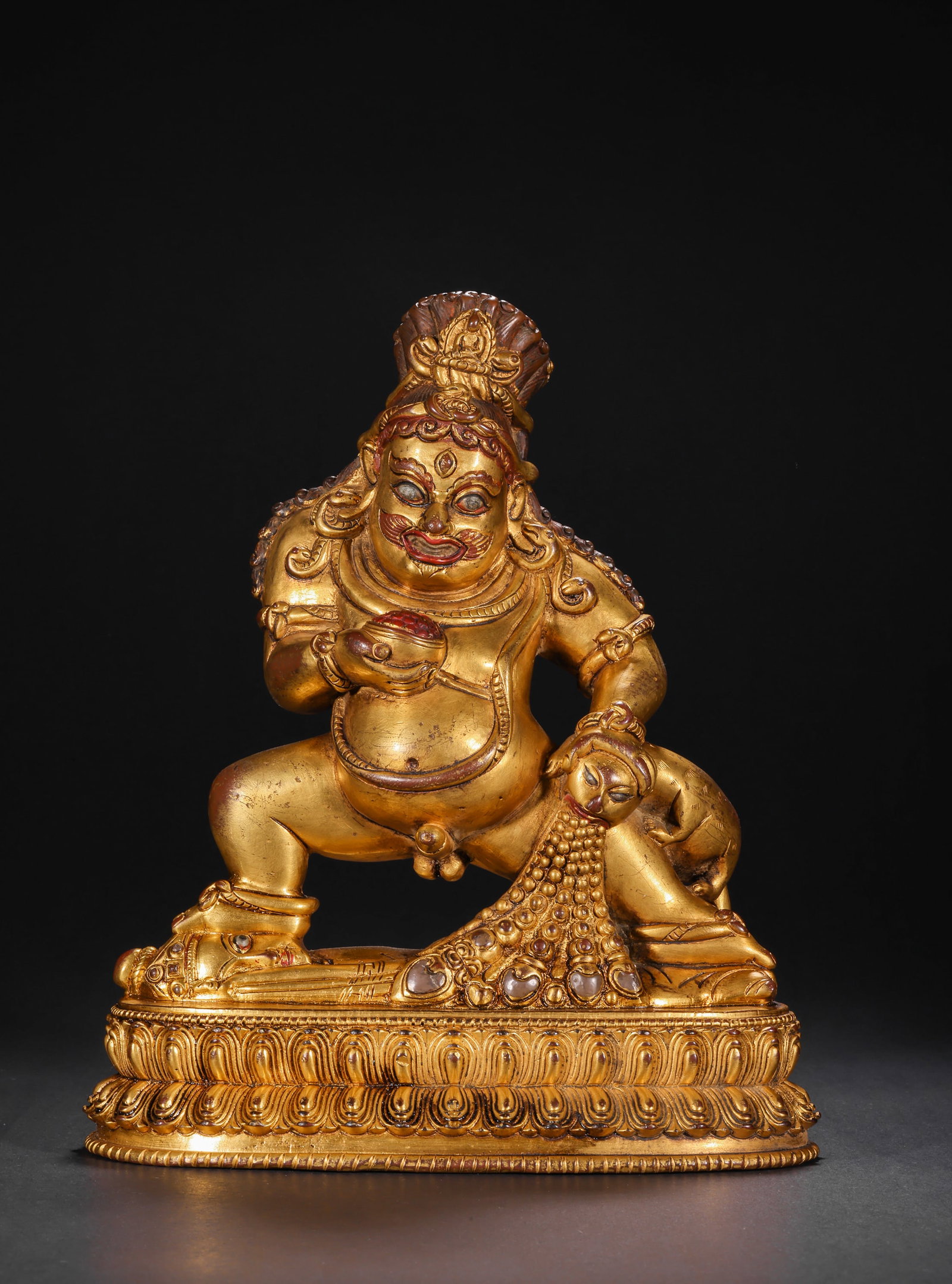 GILDED BRONZE STATUE OF THE BLACK GOD OF WEALTH FROM THE QING DYNASTY: H:23.0cm(9.06in) W:18.8cm(7.40in) Weight:2310g(5.09lb)This statue is cast in bronze and gilded. Black Jambhala stands in a vigorous posture with wide eyes and a fierce expression, holding a wish-fulfi