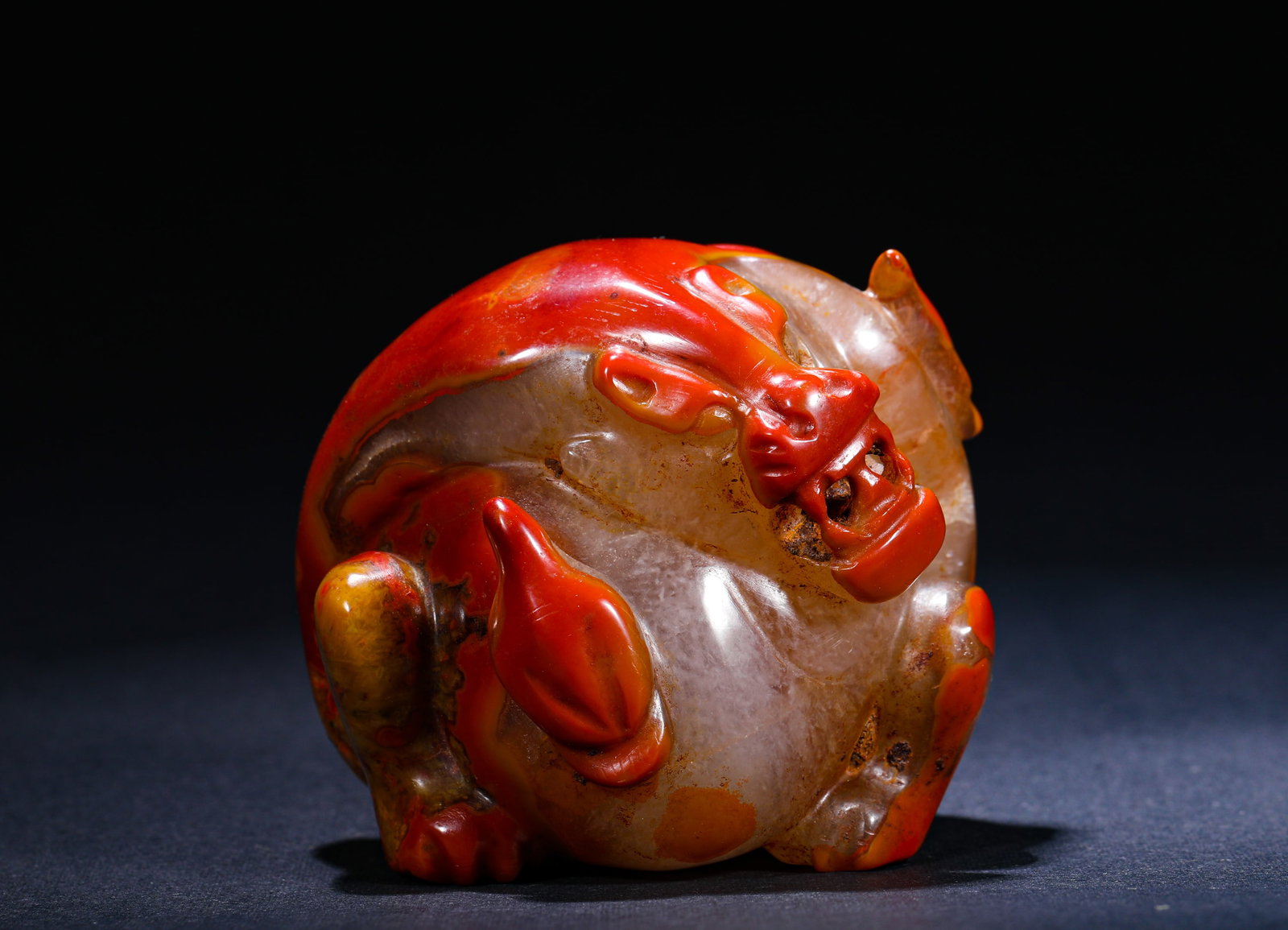 RED AGATE CARVED AUSPICIOUS BEAST HANDLE FROM THE WARRING STATES PERIOD: H:5.5cm(2.17in) W:6cm(2.36in) Weight:260g(0.57lb)This is a carved auspicious beast handlepiece made of Warring States Red Agate, featuring skillful color carving and a plump, vivid shape, a fine piece