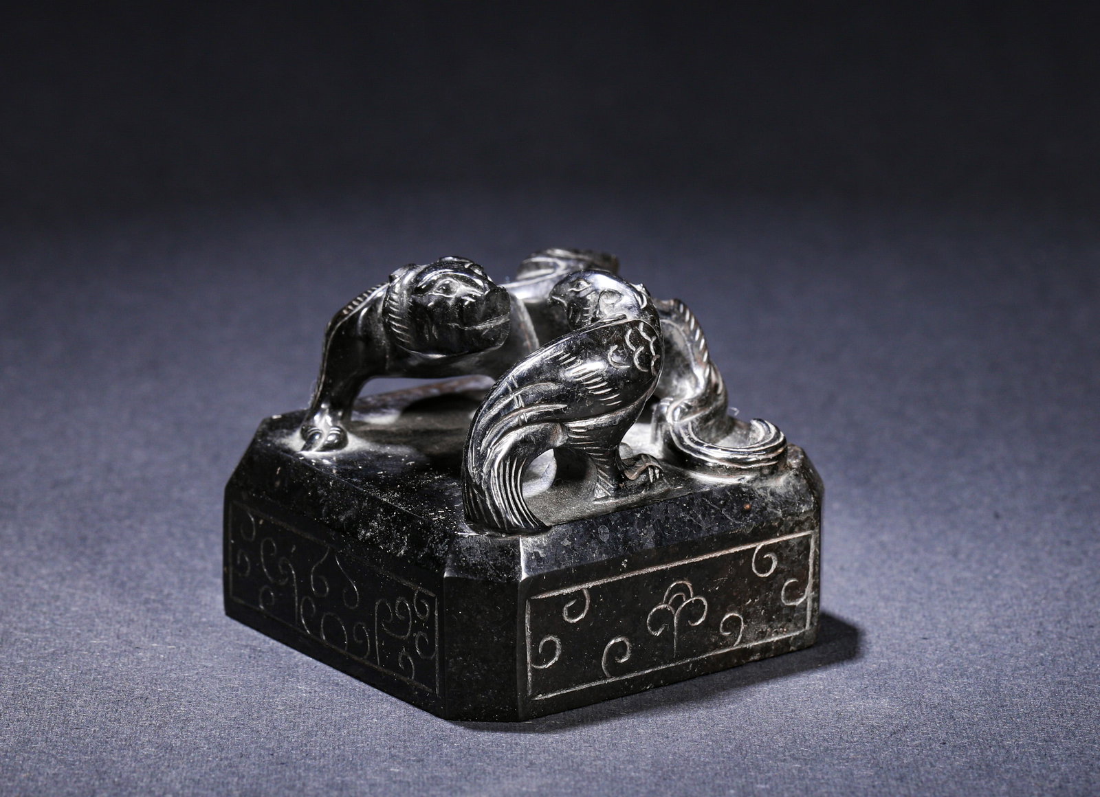A SEAL OF A DRAGON, TIGER AND STRANGE BEAST CARVED FROM COAL ESSENCE STONE FROM THE HAN DYNASTY: H:4cm(1.57in) W:5cm(1.97in) Weight:170g(0.37lb)This is a seal carved from black stone (jet) with a dragon-tiger (mythical beast) knob, decorated with cloud scroll patterns on the seal base, featuring 