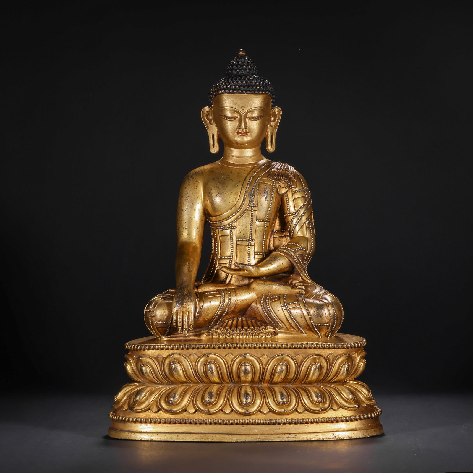 A GILDED BRONZE STATUE OF THE ENLIGHTENMENT OF SAKYAMUNI BUDDHA FROM THE QING DYNASTY: H:35.0cm(13.78in) W:22.0cm(8.66in) Weight:6450g(14.22lb)This statue is cast in bronze and gilded. Sakyamuni Buddha sits in the full-lotus posture on a double-layered lotus pedestal, with a high spiral