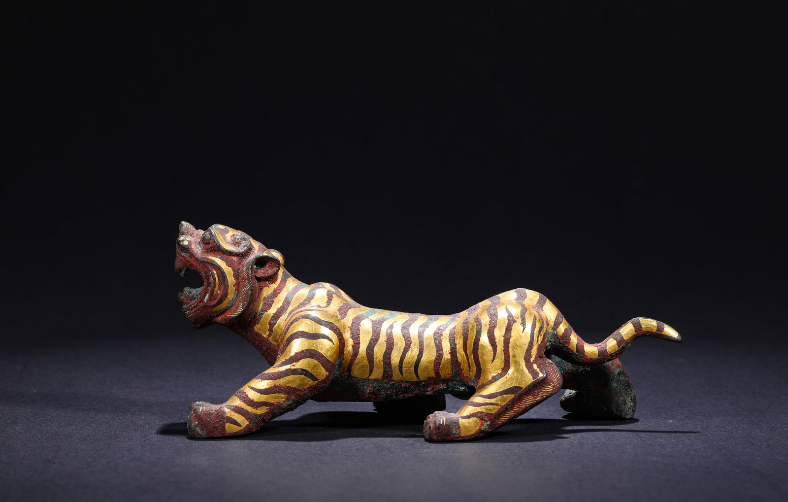 HAN DYNASTY INLAID GOLD AND SILVER TIGER-SHAPED ORNAMENTS: H:6cmW:15cmWeight:420g This is a gold-silver inlaid tiger-shaped ornament. With a bronze base, gold and silver threads are inlaid throughout the body to carve out distinct tiger stripes and eye detail