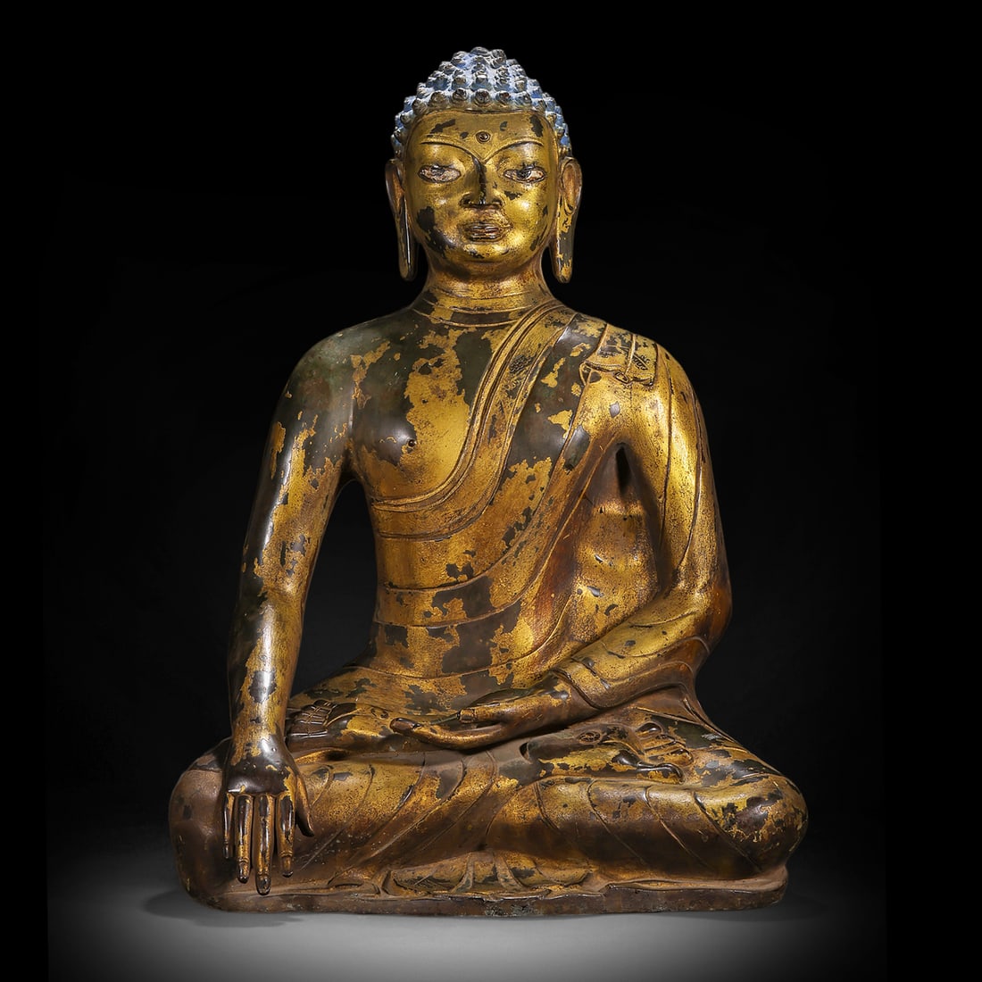 A GILDED BRONZE SEATED STATUE OF SAKYAMUNI BUDDHA FROM THE MING DYNASTY: H:58cm(22.83in) W:41cm(16.14in) Weight:23000g(50.71lb)This statue is cast in bronze and gilded. Sakyamuni Buddha sits in the lotus position, with a high ushnisha and a solemn appearance. The right han