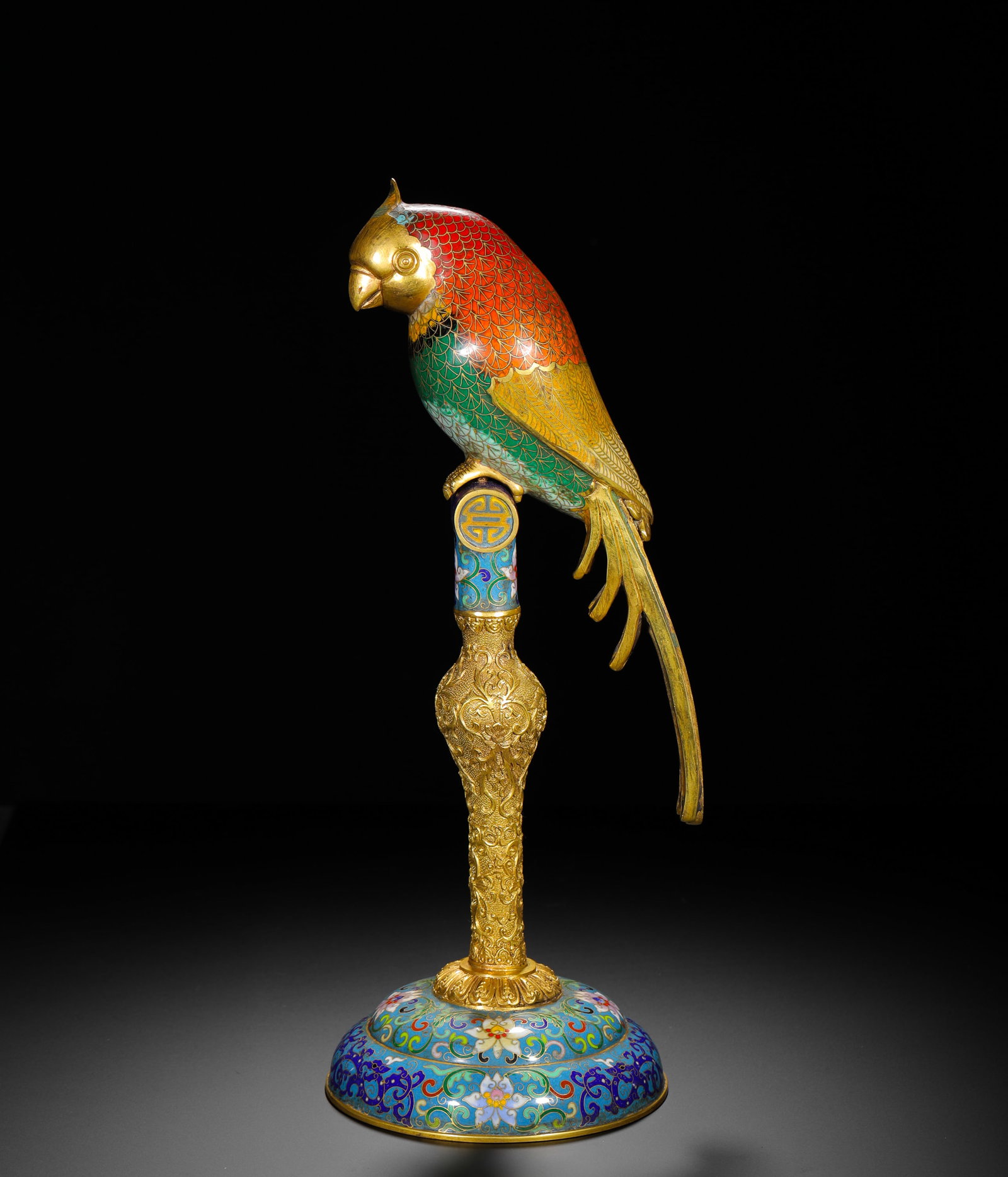 A PARROT ORNAMENT MADE IN THE QIANLONG PERIOD OF THE QING DYNASTY WITH GILDED COPPER AND CLOISONNE: H:40cm (15.75in) W:15cm (5.91in) Weight:2480g (5.47lb)Gilt bronze cloisonne parrot perched on longevity-mark pillar, flower-decorated base, Qianlong reign mark on underside.