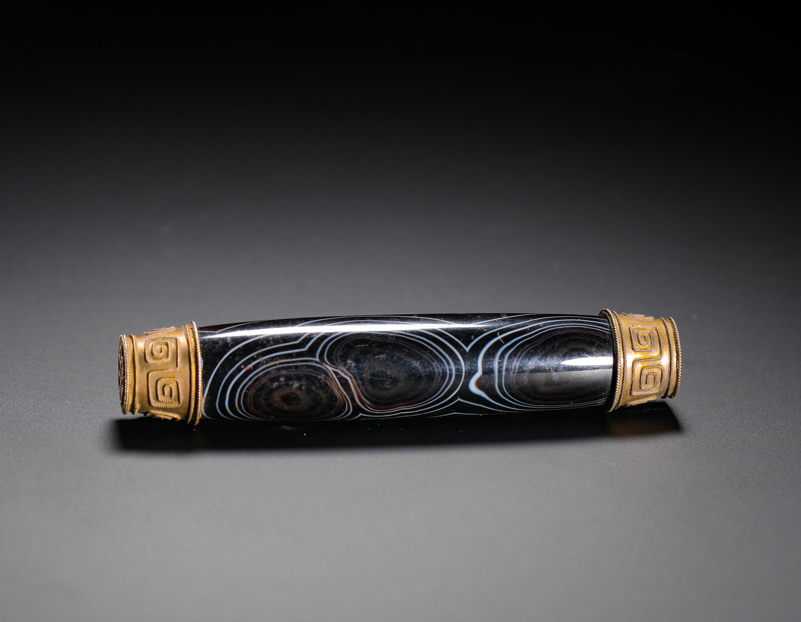 QING DYNASTY GOLD TUBE ORNAMENT WRAPPED WITH SILK AGATE: H:9.5cm(3.74in) D:2cm(0.79in) Weight:50g(0.11lb)This is a Qing Dynasty banded agate tube ornament. The main body is made of natural banded agate with distinct black-and-white layers, forming natural "