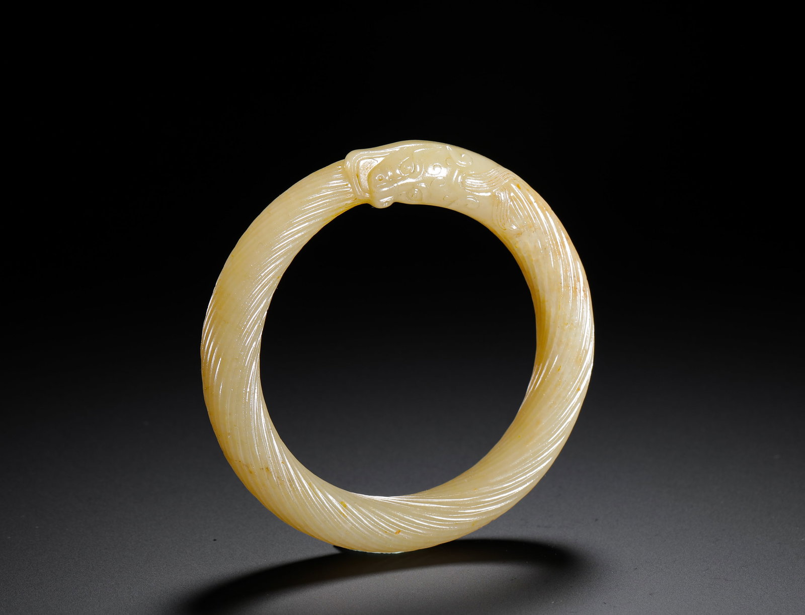 HAN HETIAN WHITE JADE TWISTED SILK DRAGON HEAD BRACELET: D:8.7cmD:6.5cmWeight:80g Twisted cable jade bangle capped with carved dragon head, elite personal jade ornament of Han Dynasty.