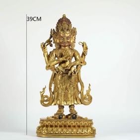 A MING DYNASTY GILDED BRONZE FOUR-ARMED GUARDIAN DEITY