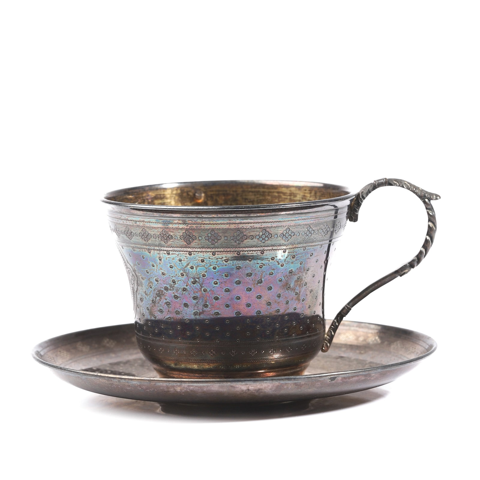 A SILVER AND IRIDESCENT ENGRAVED TEACUP AND SAUCER: Dimensions: Cup: Diameter 3 1/2 in (9 cm); Height 2 9/16 in (6.5 cm) Saucer: Diameter 5 5/8 in (14.3 cm) Weight: approx. 191.1 g Description A finely crafted silver teacup and saucer featuring a