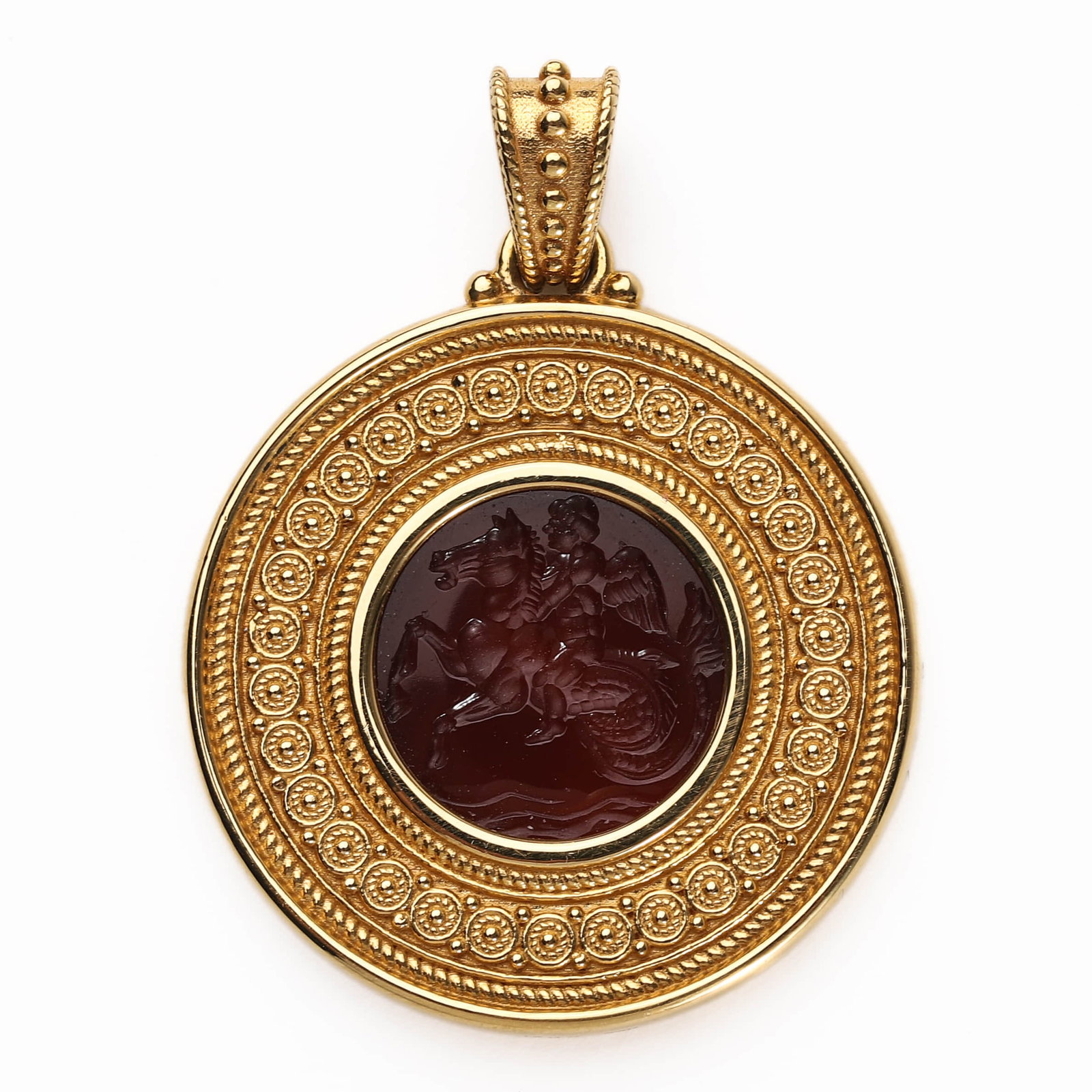 GOLD MOUNTED CARNELIAN INTAGLIO PENDANT: Dimensions: Diameter: 1 1/16 in. (26.1 mm); Weight: 14.7 g Description: This round gold-mounted pendant features a finely carved carnelian intaglio depicting a winged figure??likely Eros or a
