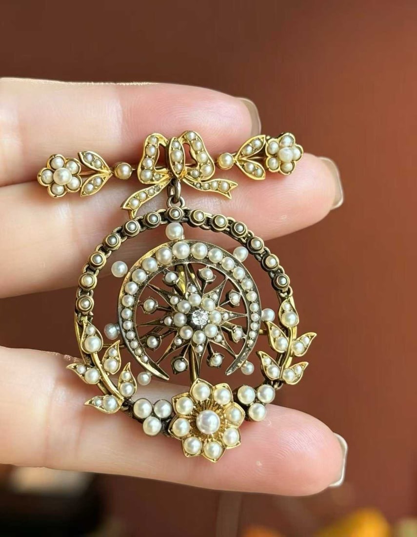 VICTORIAN 13K-16K GOLD WILD PEARL STARBURST BROOCH: Weight: 21.7g, Length: 52.2mm, Width: 44.6mm. The top features a bow design, with small flowers and leaves at both ends, a starburst at the center, and a floral wreath surrounding it. The