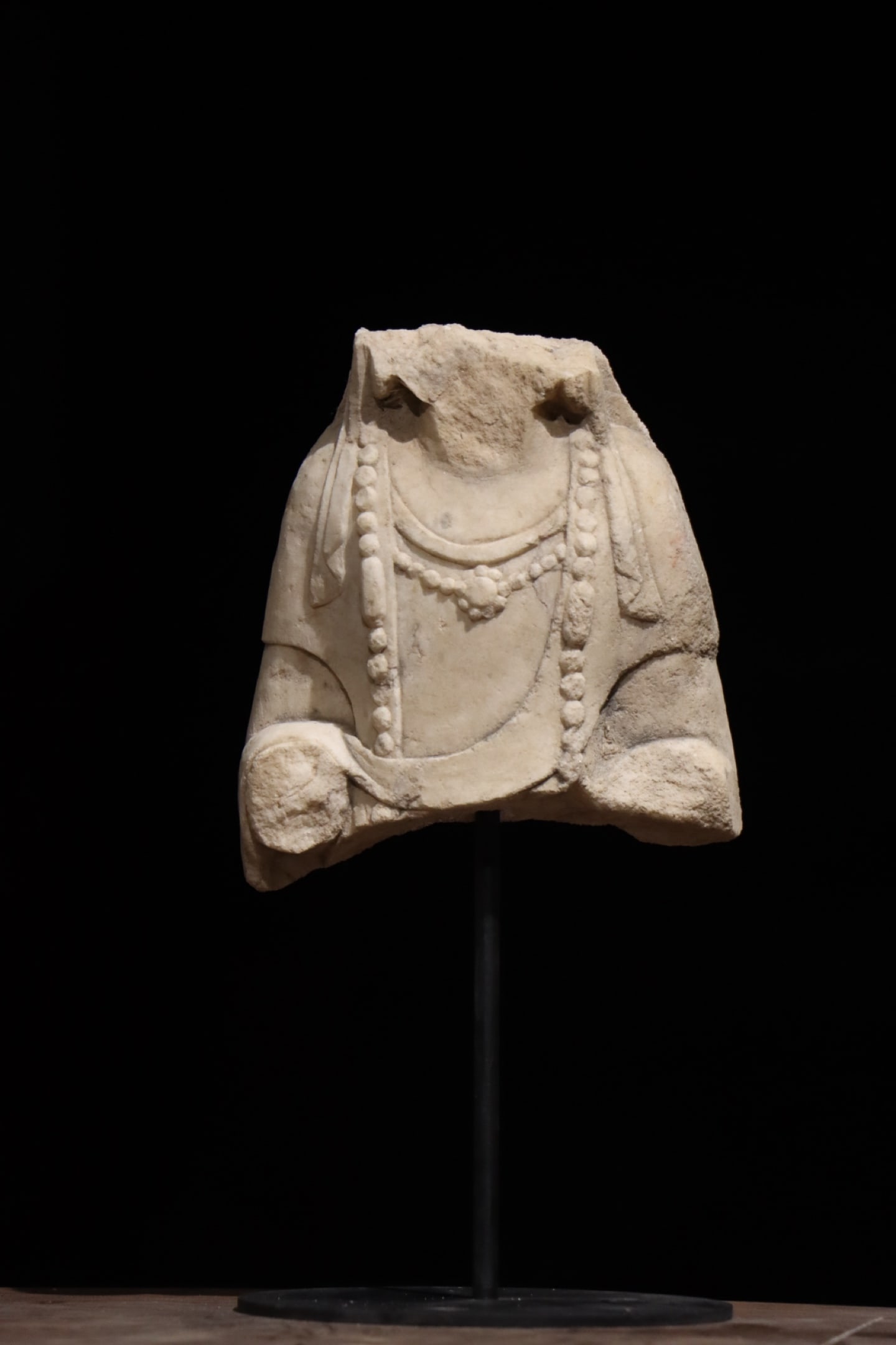 A WHITE MARBLE STATUE OF A BODHISATTVA FROM THE NORTHERN QI DYNASTY WITH A BROKEN UPPER BODY: H: 30cm (11.81in) H: 17cm (6.69in) W: 15cm (5.91in) Carved from a single block of white marble; only torso and partial arms remain, adorned with two layers of finely incised beaded necklaces, a surviv
