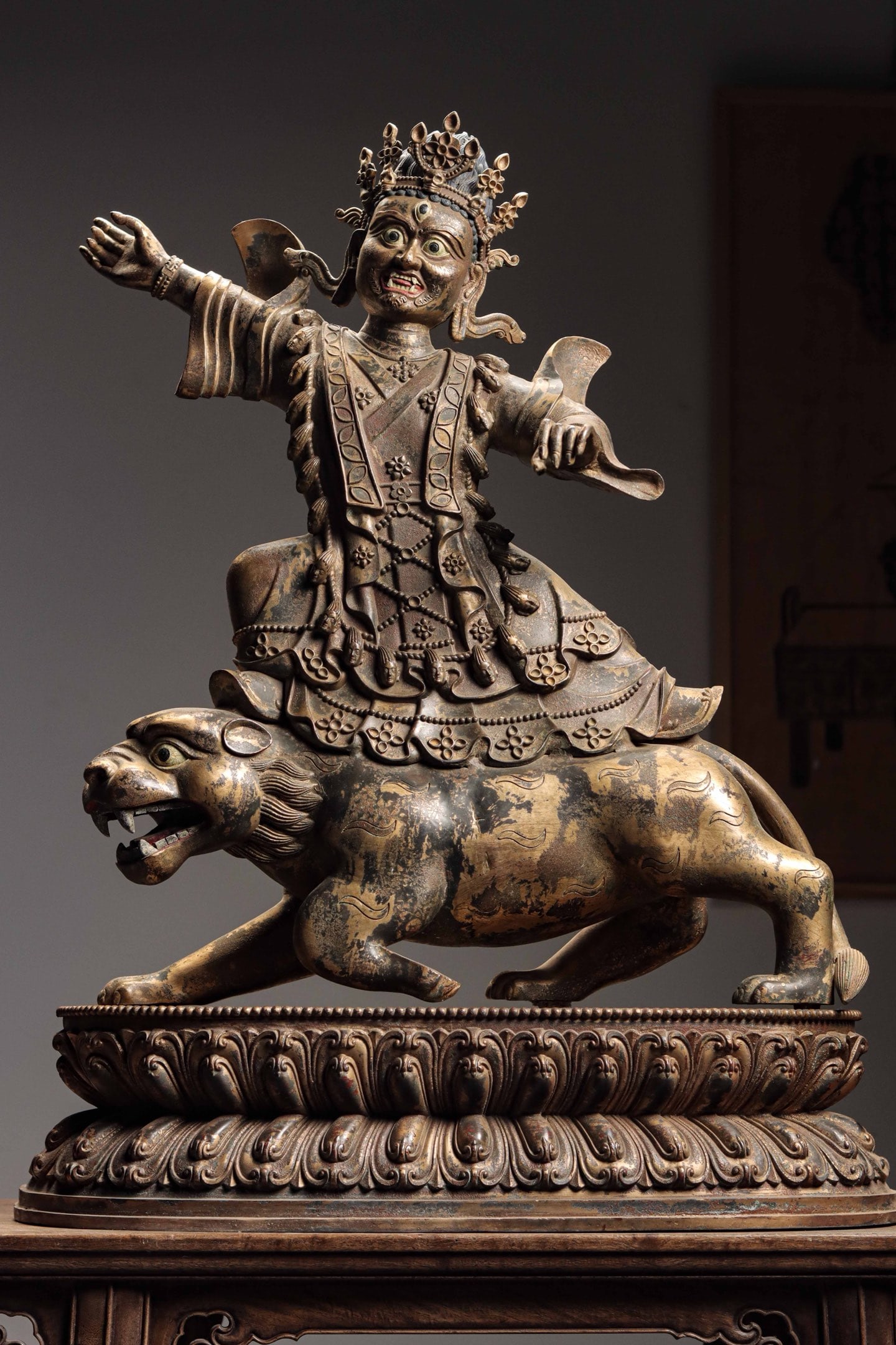 GILDED BRONZE LION PROTECTOR GOD OF WEALTH FROM THE QING DYNASTY: Weight: 30000g (66.14lb) H: 81cm (31.89in) W: 63cm (24.80in) T: 26cm (10.24in)Finely cast bronze with partial gilding on crown and robes; wrathful facial features atop walking lion, double-layer lotus