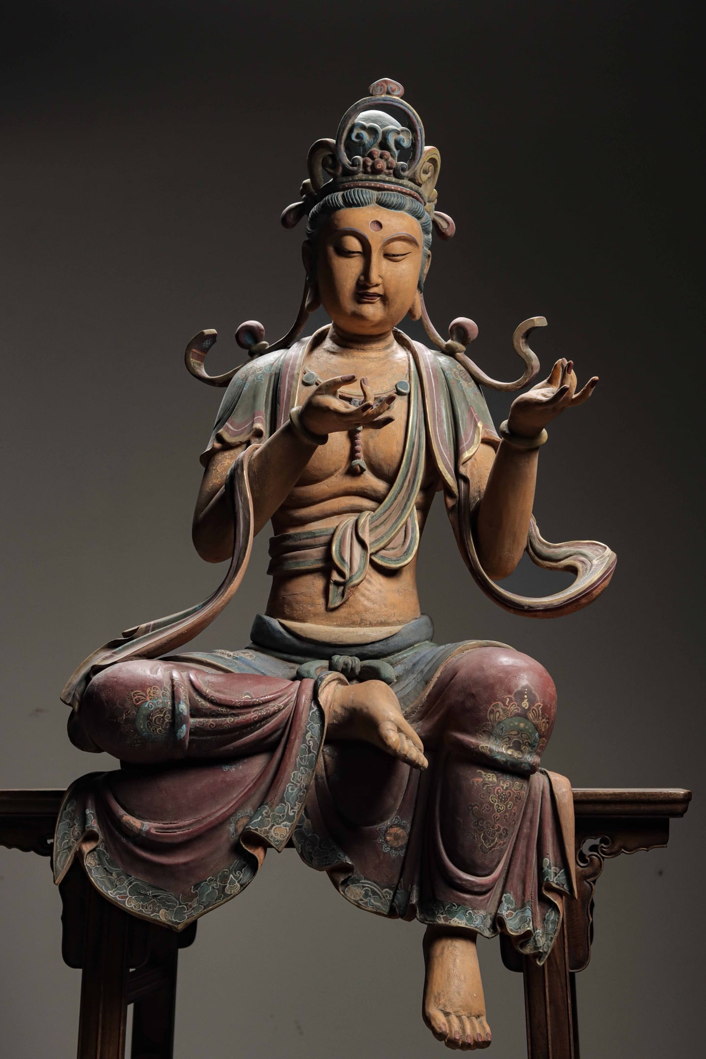 SONG DYNASTY WOODCARVING, PAINTED LACQUER, SEATED GUANYIN: H: 118cm(46.46in)W: 65cm(25.59in)T: 42cm(16.54in)This sculpture depicts Avalokite?vara in a relaxed half-lotus sitting posture, wearing an exquisite crown with gentle serene merciful facial features a