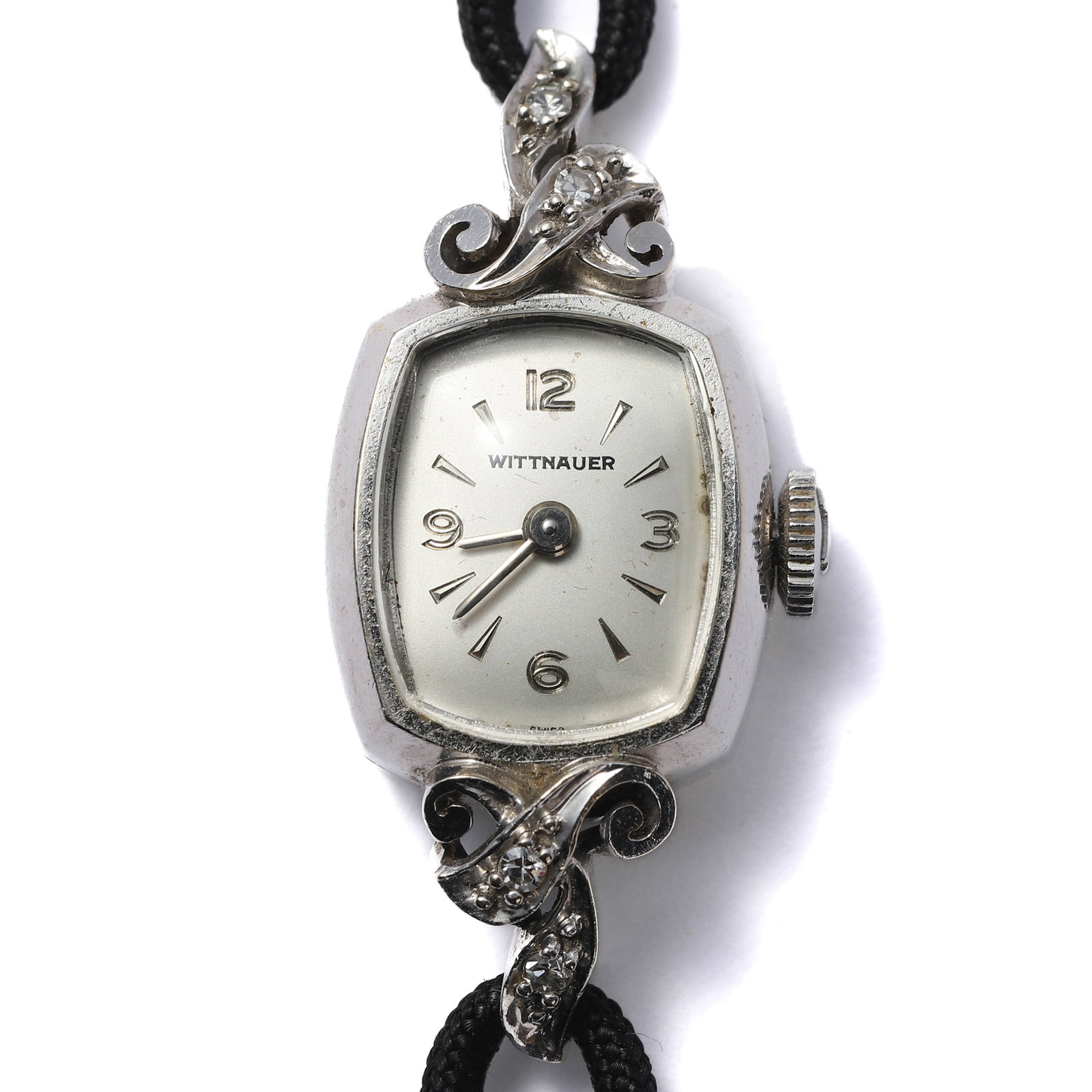 A VINTAGE WITTNAUER 14K WHITE GOLD LADIES WRISTWATCH: length: 18 in (45.7 cm); dial diameter: 5/8 in (1.5 cm) This elegant vintage ladies wristwatch by Wittnauer features a tonneau-shaped case crafted in 14K white gold, adorned with intricate scrollwork