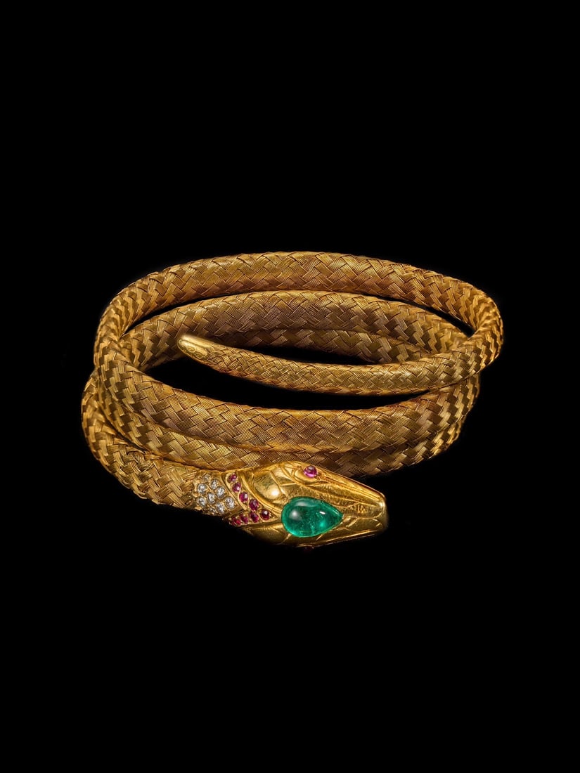 Late-19th-Century Victorian Period 18K Gold Emerald Ruby Diamond Woven-Gold Flexible Snake Bangle: Bracelet Length:56.5cmWt:44.19g A bangle woven from multiple strands of gold wire, modelled in a coiled serpent form. A cabochon-cut emerald is set atop the serpent's head, rubies accent its eyes, wit