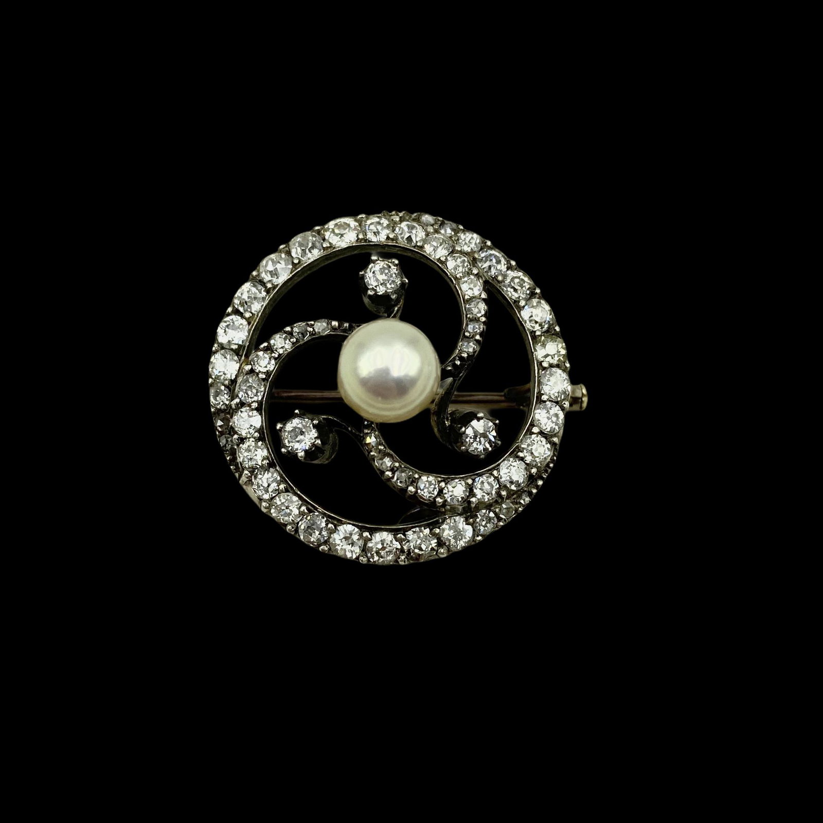 18K Edwardian Diamond Pearl Circle Brooch: Stylized Circle with graduated old mine cut diamonds and a pearl center. Pearl measures 7.5mm, apx 3 CTW.Hallmarked and 18K stamped on pin. Measures 30mm Dia. Weight 9.1 grams