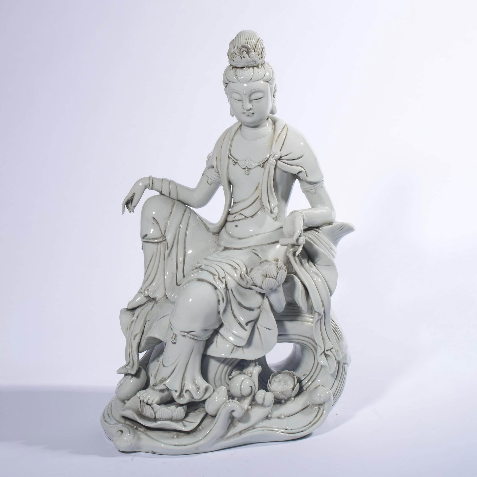 A Sitting Porcelain Guanyin Statue: The craftsmanship of this Guanyin statue is complex and exquisite, using stamping , cut , dough and other decorative techniques. The white glaze is bright and lustrous, and the body is delicate. The s