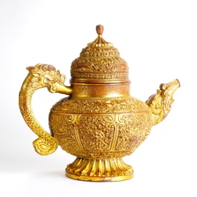 A TIBETAN GILT-BRONZE SCROLL LOTUS DRAGON-HANDLED EWER