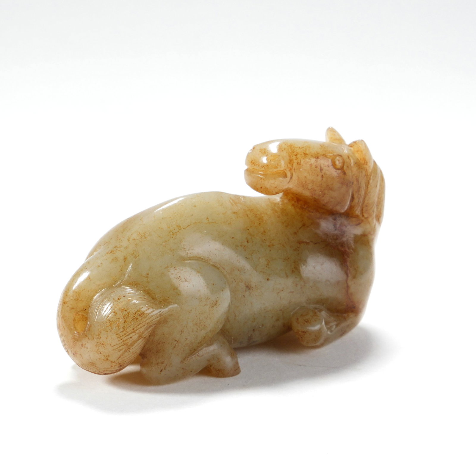 A HETIAN JADE LYING HORSE ORNAMENT (WITH ARTIFICIAL COLORATION): A HETIAN JADE LYING HORSE ORNAMENT (WITH ARTIFICIAL COLORATION) H:3.5CM,W:6.5CM
