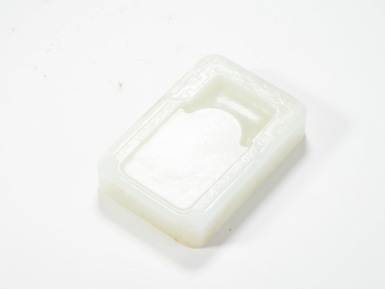 A HETIAN WHITE JADE INK STONE SHAPED PAPER WEIGHT WITH MEANDER PATTERN: A HETIAN WHITE JADE INK STONE SHAPED PAPER WEIGHT WITH MEANDER PATTERN H:1.8CM,L:9.5CM,W:6.2CM