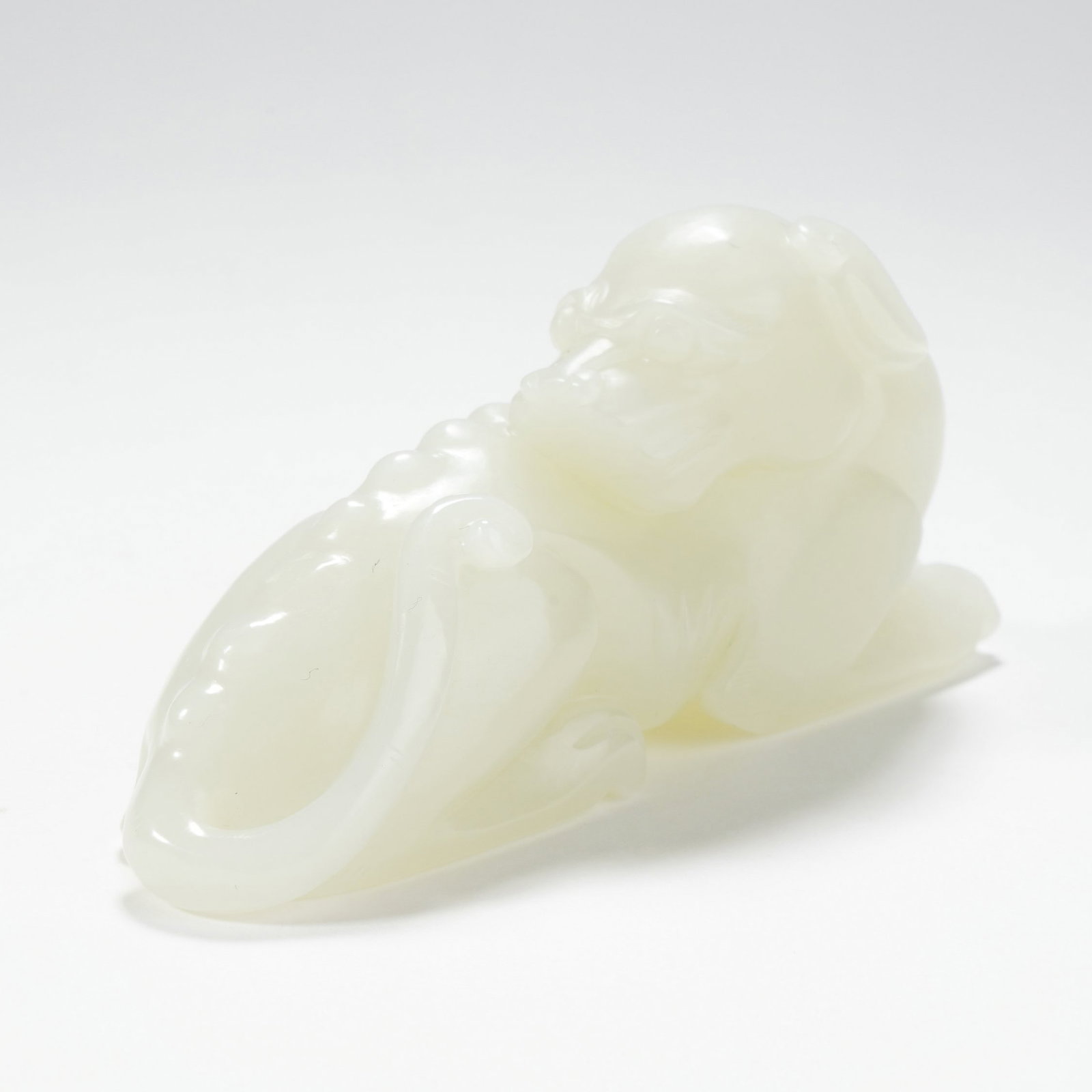 A HETIAN WHITE JADE CARVED AUSPICIOUS BEAST PAPER WEIGHT: A HETIAN WHITE JADE CARVED AUSPICIOUS BEAST PAPER WEIGHT H:4CM,W:9CM