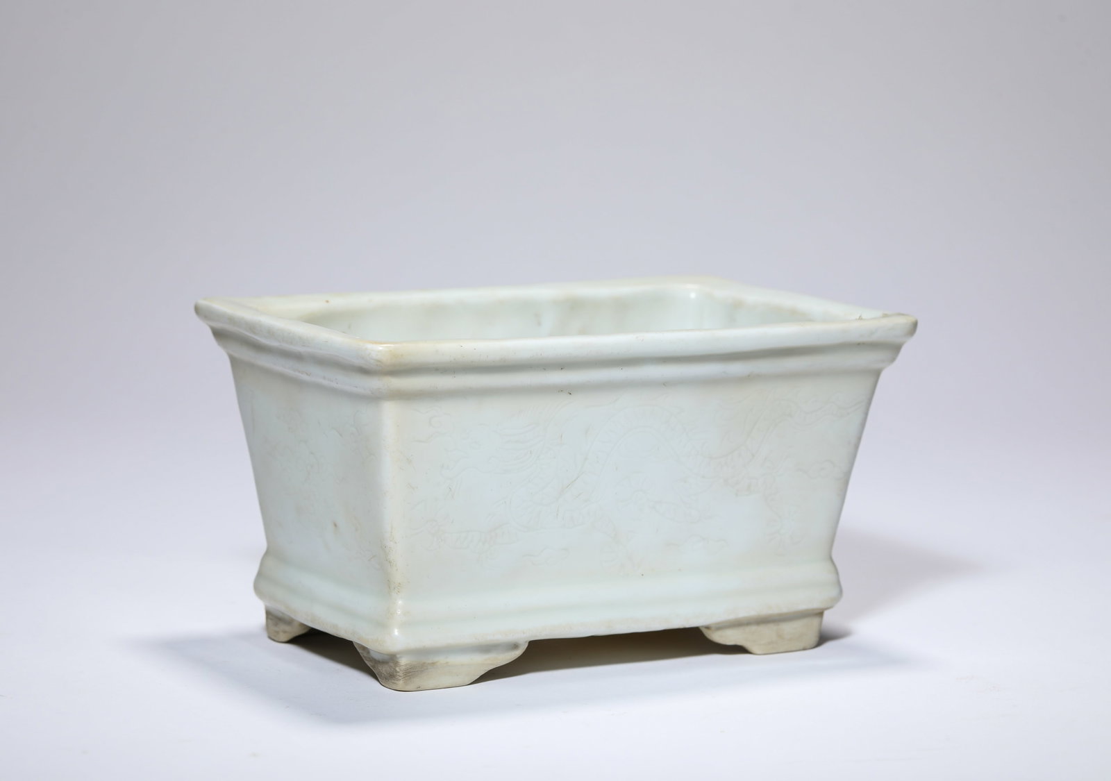 A WHITE-GLAZED ‘ANHUA CARVED DRAGON AND CLOUDS’ BASIN: A WHITE-GLAZED ‘ANHUA CARVED DRAGON AND CLOUDS’ BASIN Description: Dimensions: Length: 15.7 cm x Width: 10.5 cm x Height: 8.6 cm. All measurements are approximate.