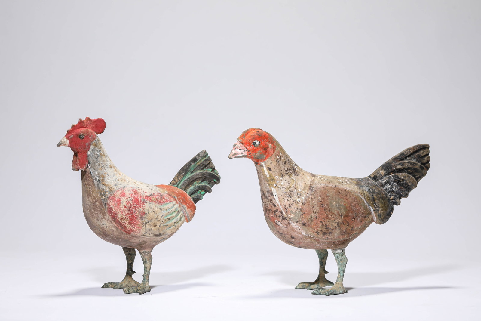 A PAIR OF PAINTED POTTERY ROOSTERS: A PAIR OF PAINTED POTTERY ROOSTERS Description: Dimensions: Length: 15.8 cm x Width: 6.5 cm x Height: 15.5 cm.imensions: Length: 20.2 cm x Width: 6.6 cm x Height: 14.3 cm. All measurements are