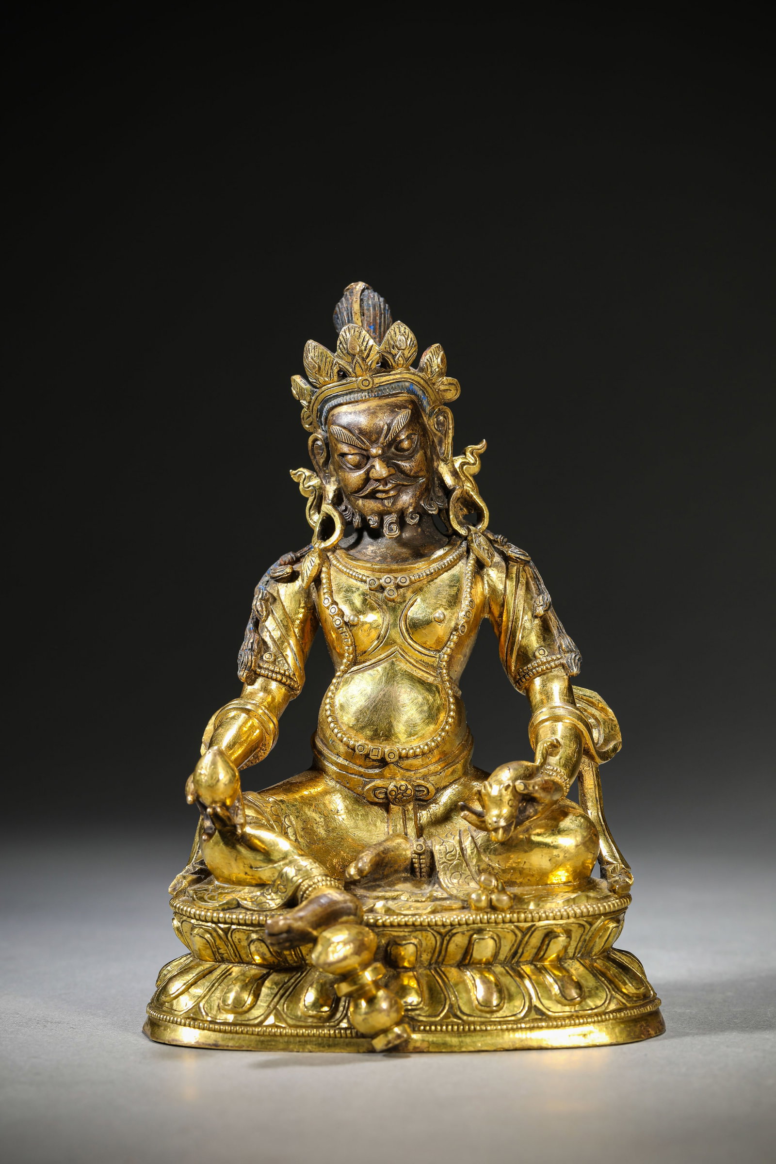 A GILT-BRONZE FIGURE OF A JAMBHALA: A GILT-BRONZE FIGURE OF A JAMBHALA Description: Dimensions: Weight: 1300 g. Length: 11.6 cm x Width: 8.5 cm x Height: 16.8 cm. All measurements are approximate.