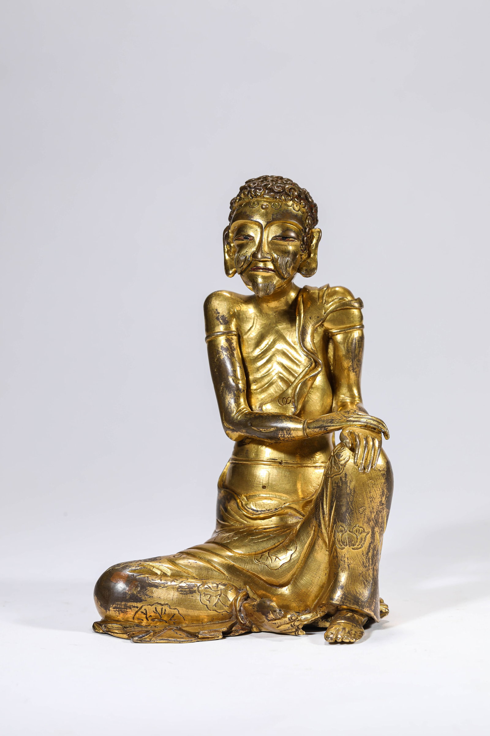 A GILT-BRONZE FIGURE OF AN ARHAT: A GILT-BRONZE FIGURE OF AN ARHAT Description: Dimensions: Weight: 1334 g. Length: 10.7 cm x Width: 11 cm x Height: 16.7 cm. All measurements are approximate.