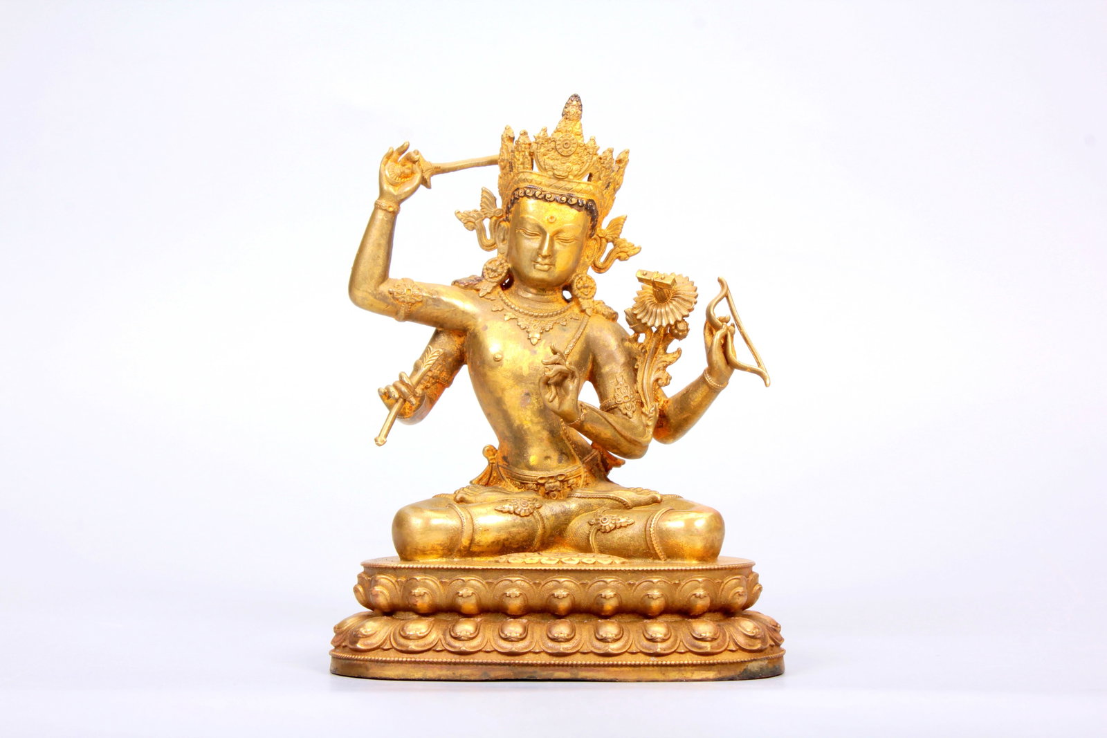 A GILT-BRONZE FIGURE OF FOUR-ARMED MANJUSHRI: A GILT-BRONZE FIGURE OF FOUR-ARMED MANJUSHRI Size:Height:10.3cm,Width:7.8cm;Weight:487grams