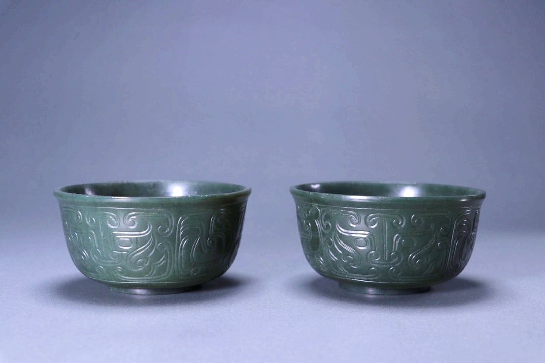 A PAIR OF HETIAN SPINACH JADE BOWLS WITH TAOTIE MASKS: A PAIR OF HETIAN SPINACH JADE BOWLS WITH TAOTIE MASKS Size:Diam:9.5cm,Height:5.3cm;Weight:308grams