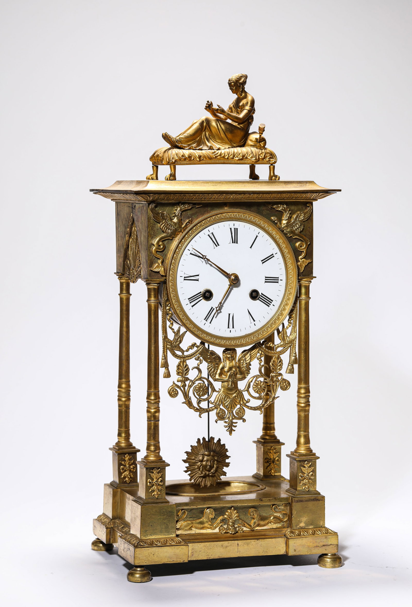 A GILT-BRONZE CLOCK: A GILT-BRONZE CLOCK Description: Dimensions: Weight: 7300 g. Length: 22.3 cm x Width: 16.8 cm x Height: 49.5 cm. All measurements are approximate.