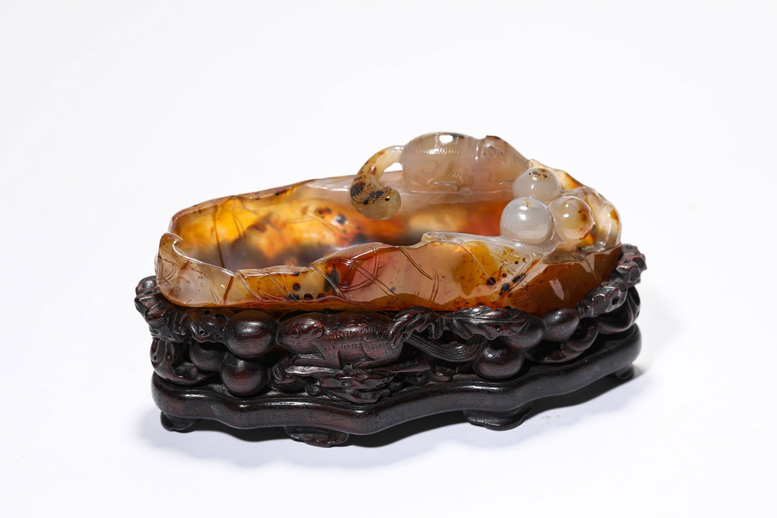 AN AGATE 'CARVED SQUIRREL AND GRAPE' 'LOTUS LEAF-FORM' BRUSH WASHER: AN AGATE 'CARVED SQUIRREL AND GRAPE' 'LOTUS LEAF-FORM' BRUSH WASHER Description: Dimensions: Length: 13.7 cm x Width: 6.5 cm x Height: 4.8 cm. All measurements are approximate.