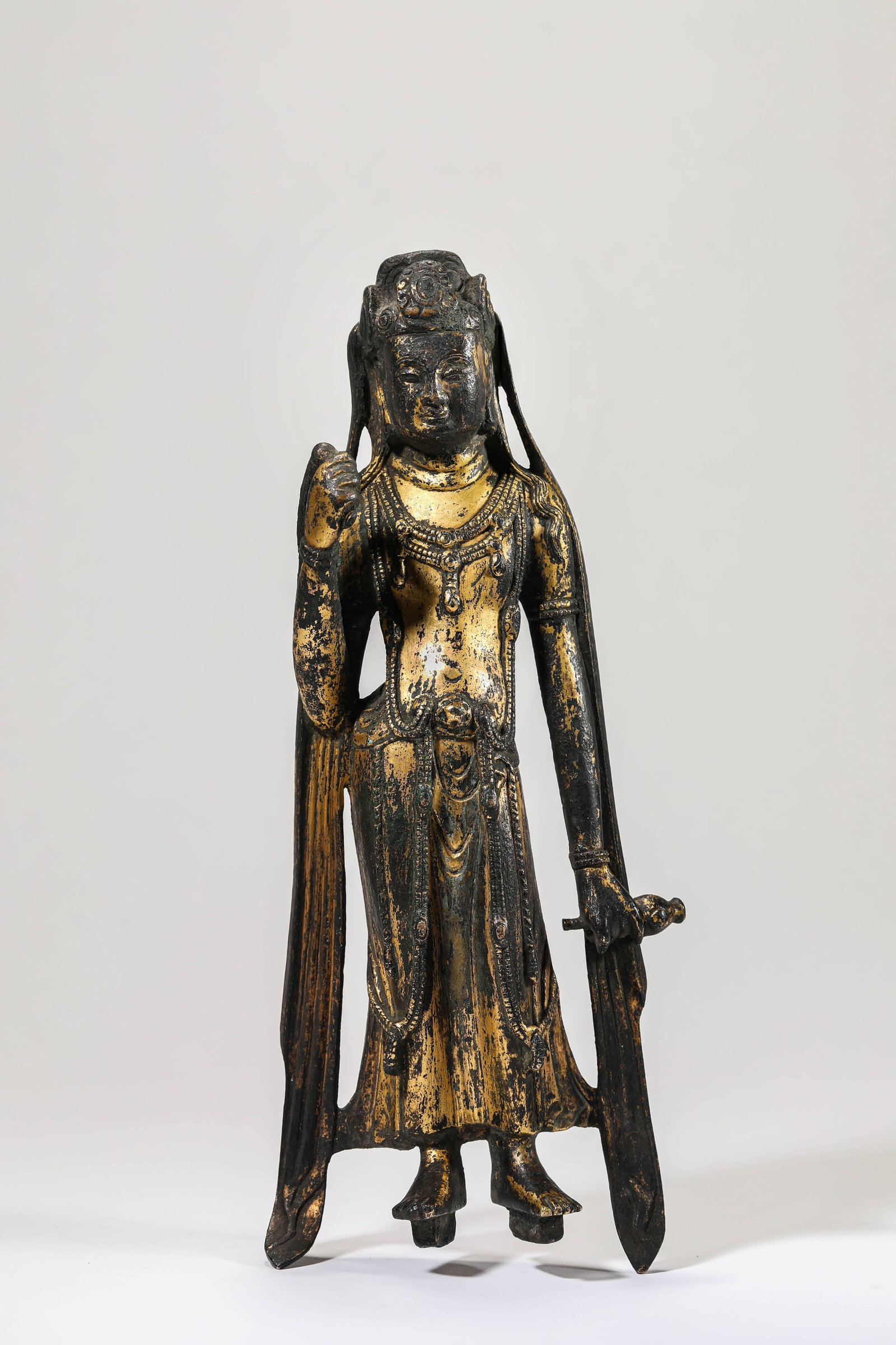 A GILT-BRONZE STANDING FIGURE OF AVALOKITESHVARA: A GILT-BRONZE STANDING FIGURE OF AVALOKITESHVARA Description: Dimensions: Weight: 1181 g. Length: 11.2 cm x Width: 7.8 cm x Height: 29 cm. All measurements are approximate.