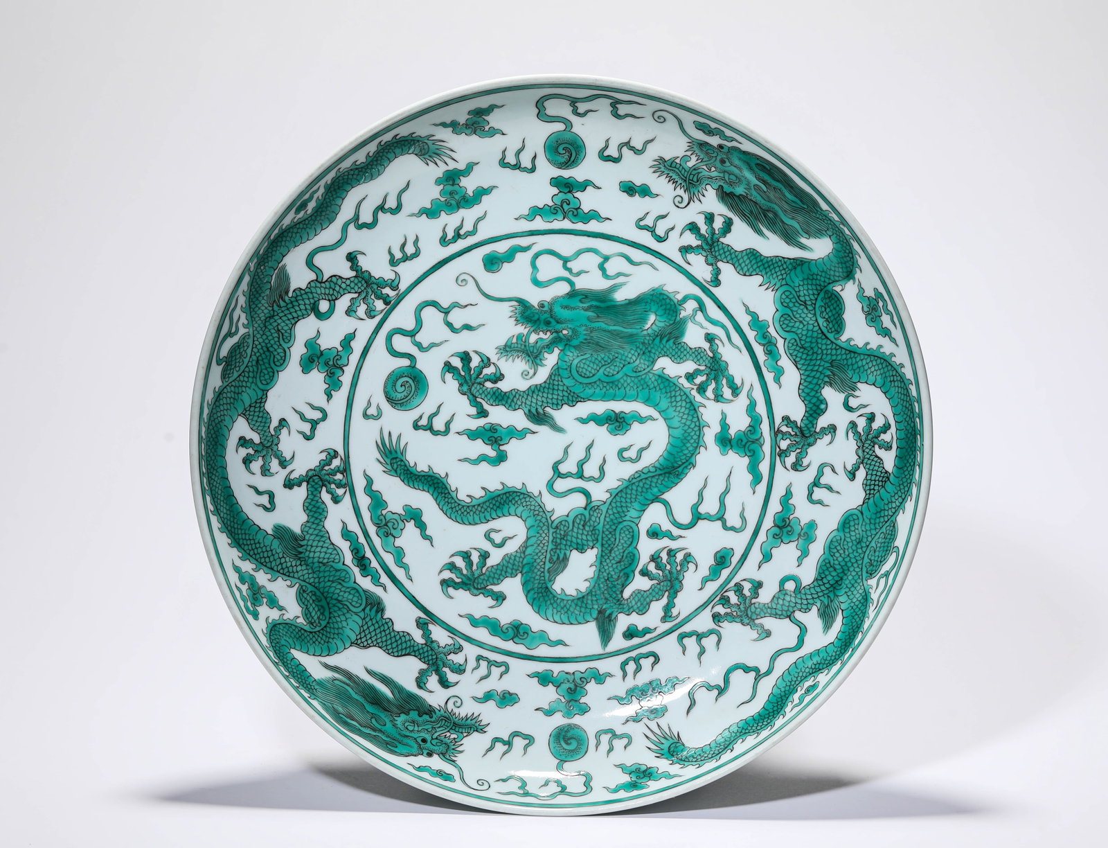 A GREEN-GLAZED 'DRAGON AND CLOUDS' DISH: A GREEN-GLAZED 'DRAGON AND CLOUDS' DISH Description: Dimensions: Width: 32.5 cm x Height: 5.8 cm. All measurements are approximate.